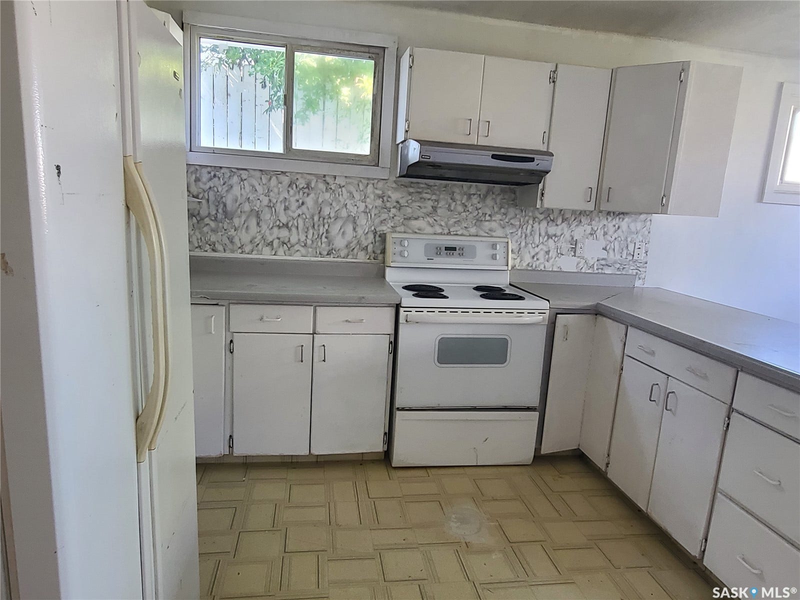 White cabinetry with integrated range, range hood, and refrigerator