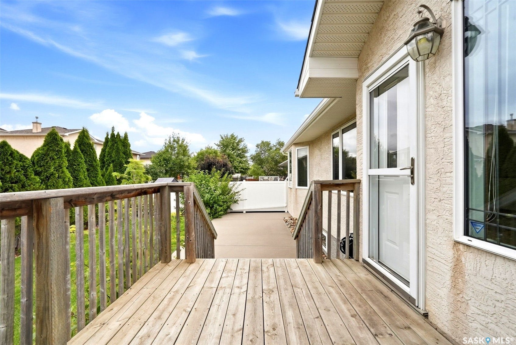 Wood deck with a full-light storm door and exterior wall lantern