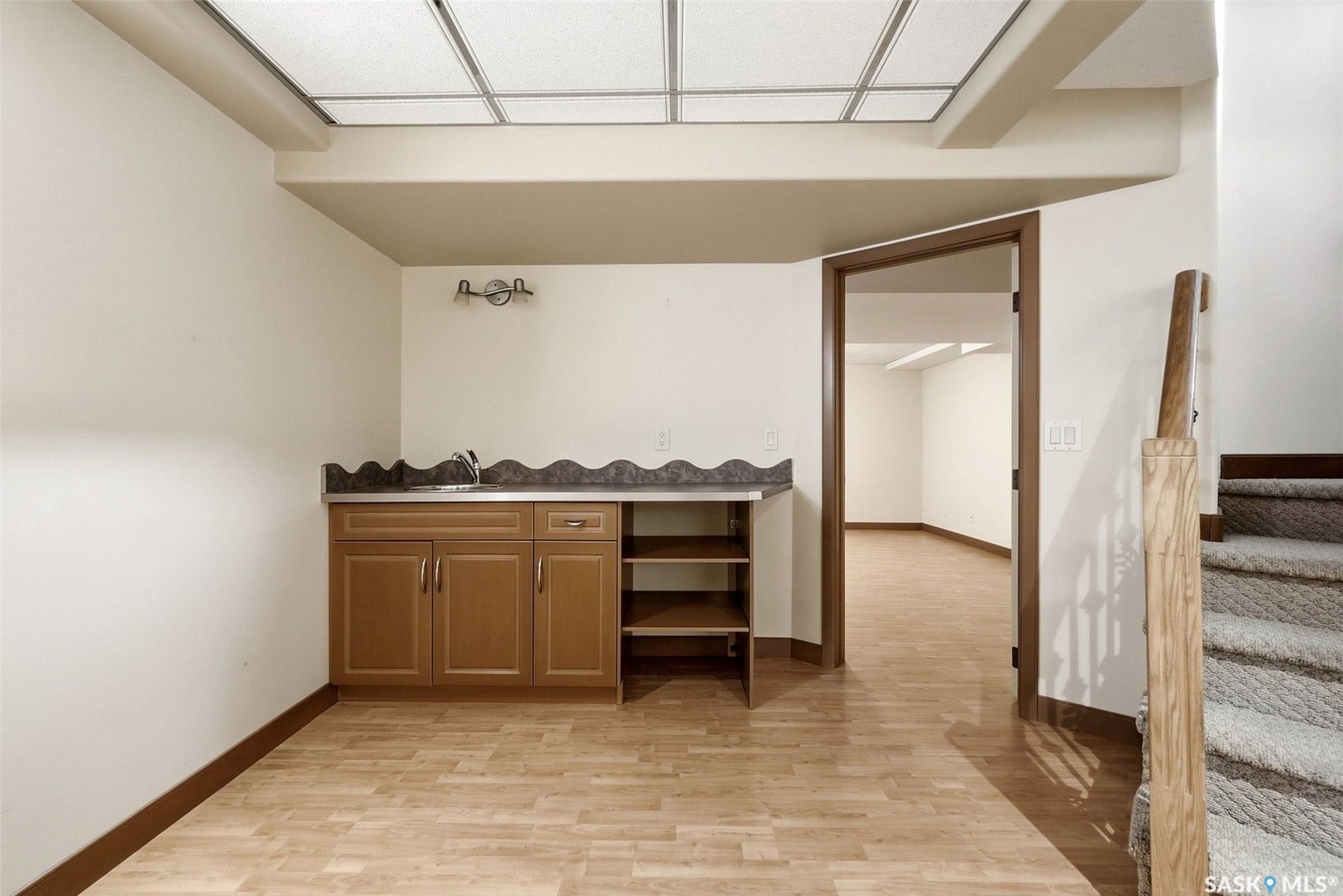 Built-in cabinetry with a sink, wood-finish flooring, and a carpeted staircase