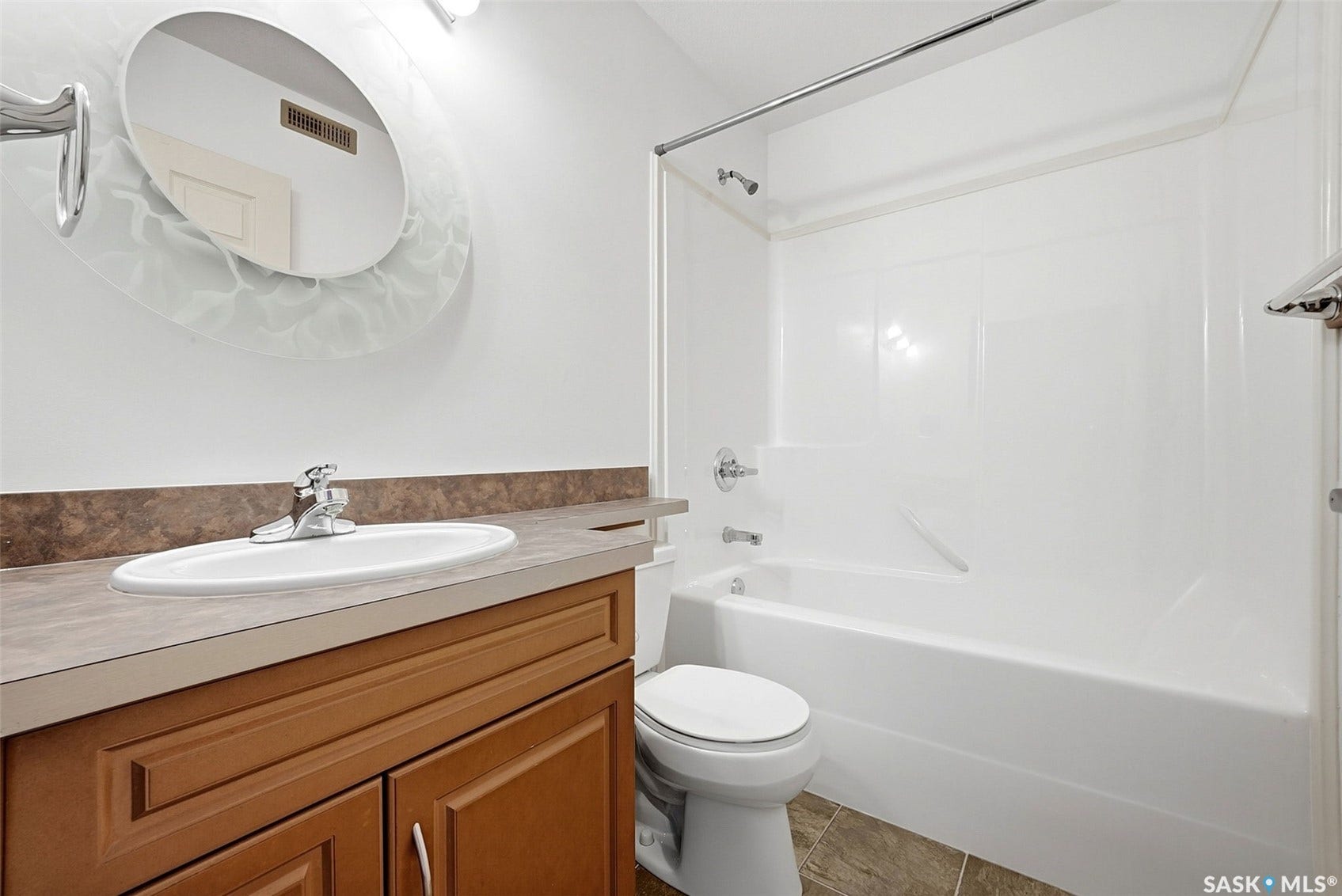 Bathroom featuring a wood-finish vanity with an integrated sink, a full bathtub with shower, and tile flooring