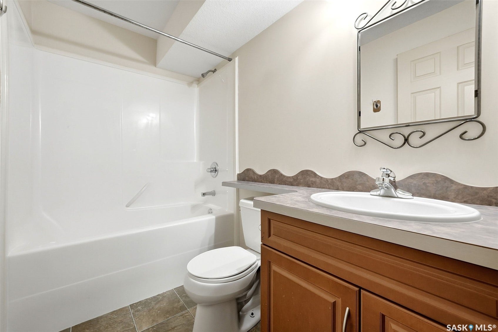 White tub and shower combination with chrome fixtures, wood-finish vanity, and a rectangular undermount sink with a chrome faucet