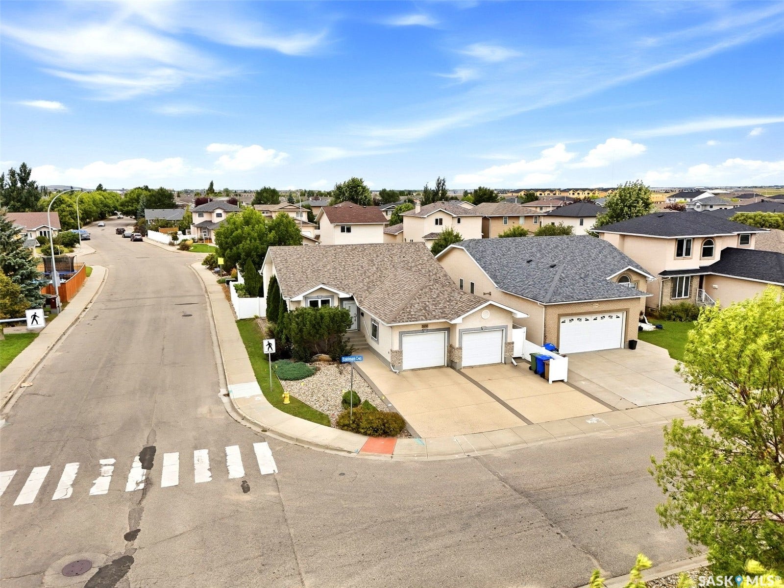 Corner lot residence featuring a paved driveway, attached two-car garage, and a landscaped front yard with decorative rocks and shrubbery