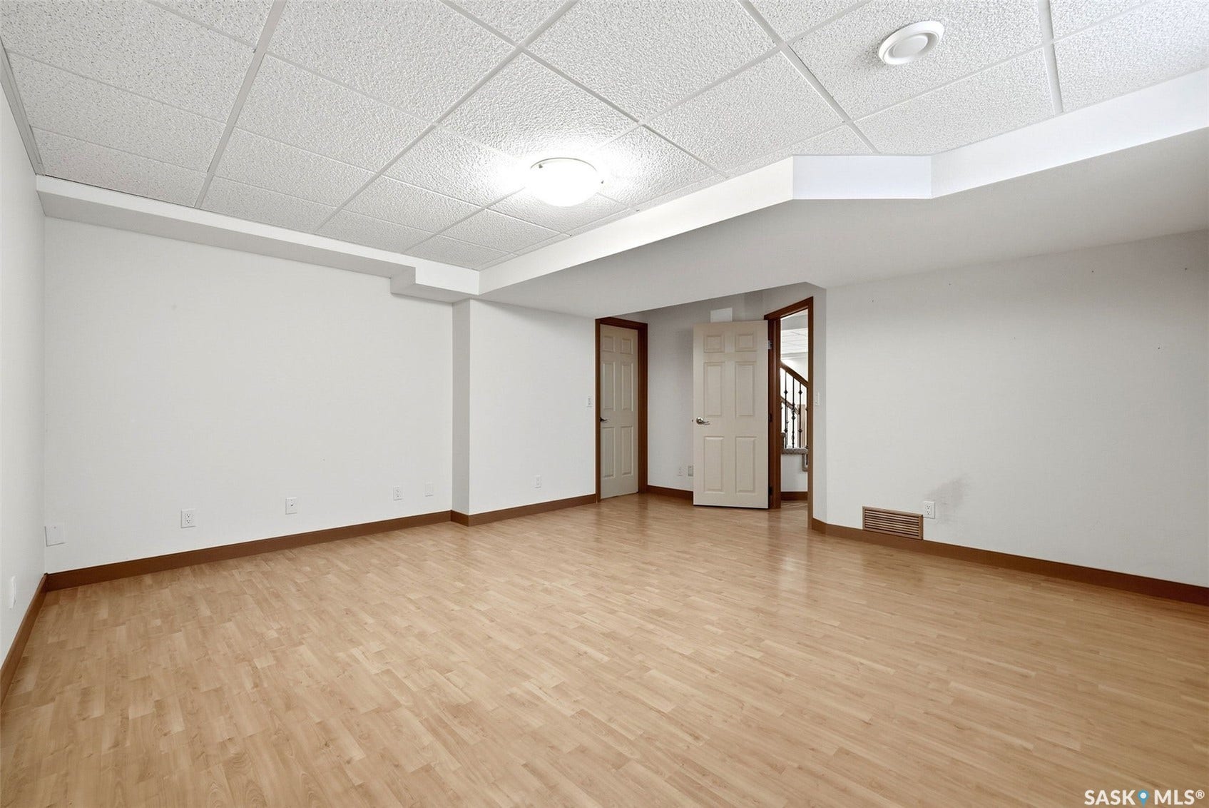 Expansive room with wood-finish flooring and white walls