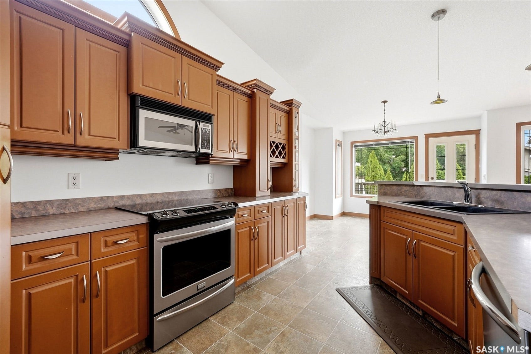 Kitchen featuring extensive wood cabinetry, stainless steel appliances, tiled flooring, and a built-in wine rack