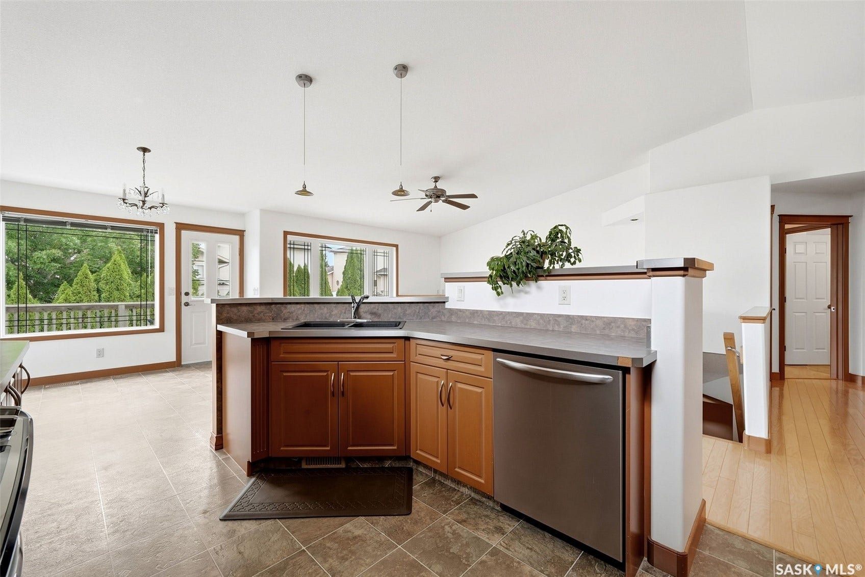 Spacious kitchen island with rich wood cabinetry and stainless steel appliances, anchored by a gray countertop and complemented by pendant lighting