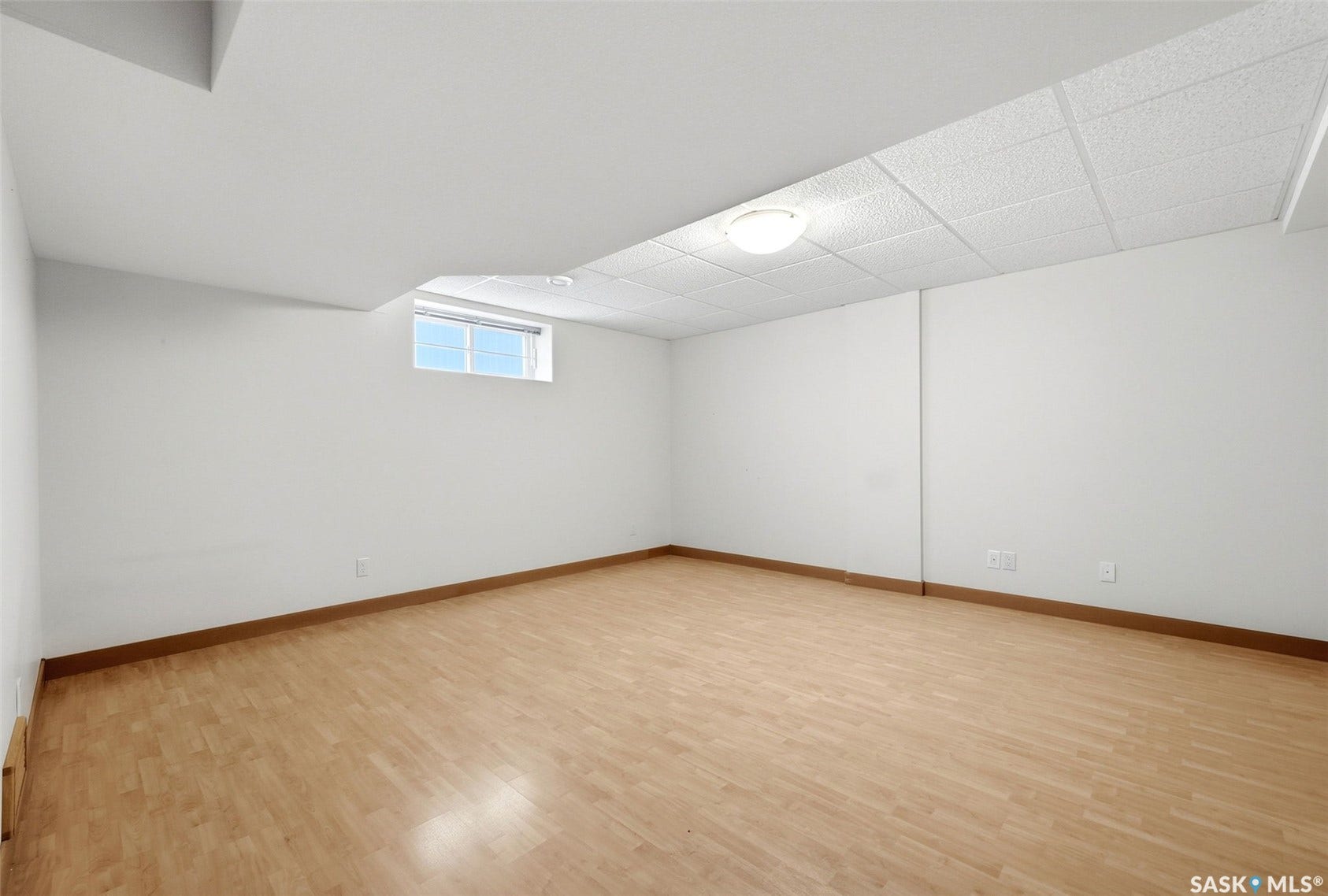 Wood-finish flooring, drop ceiling with recessed lighting, and a white-framed window