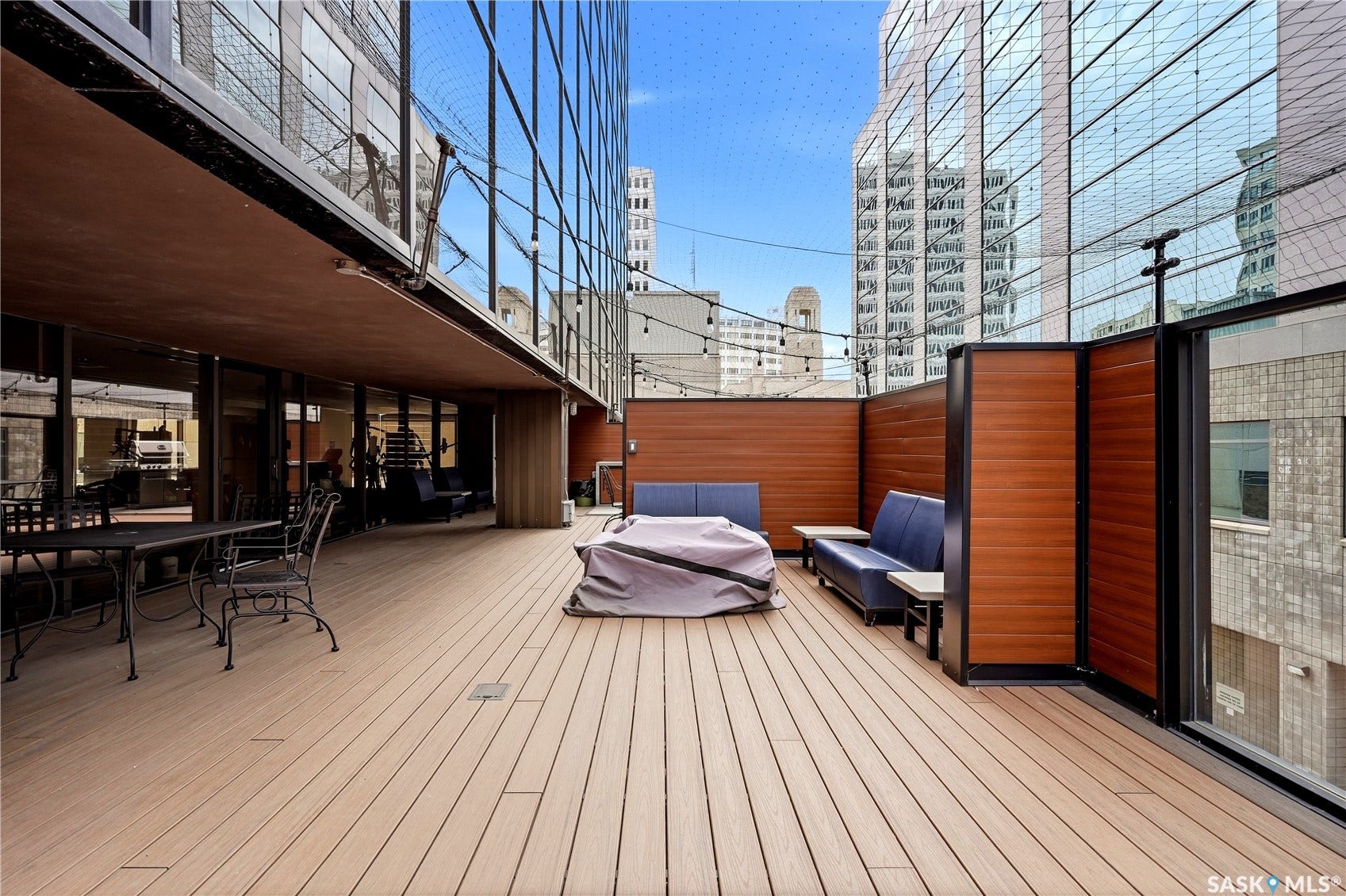 1914 Hamilton Street, #1007, Regina SK S4P 3N6 Expansive outdoor deck featuring wood-finish decking, privacy panels, and a glass-enclosed railing system