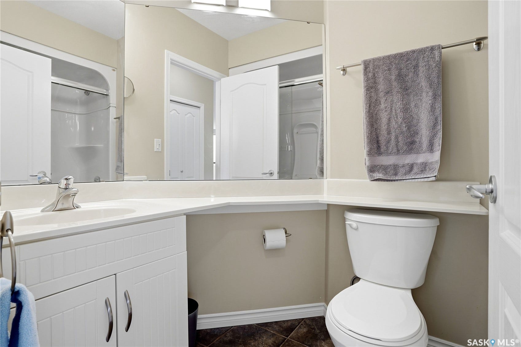 1914 Hamilton Street, #1007, Regina SK S4P 3N6 Vanity with integrated sink and chrome faucet, large wall-mounted mirror, white paneled cabinetry, and tiled flooring