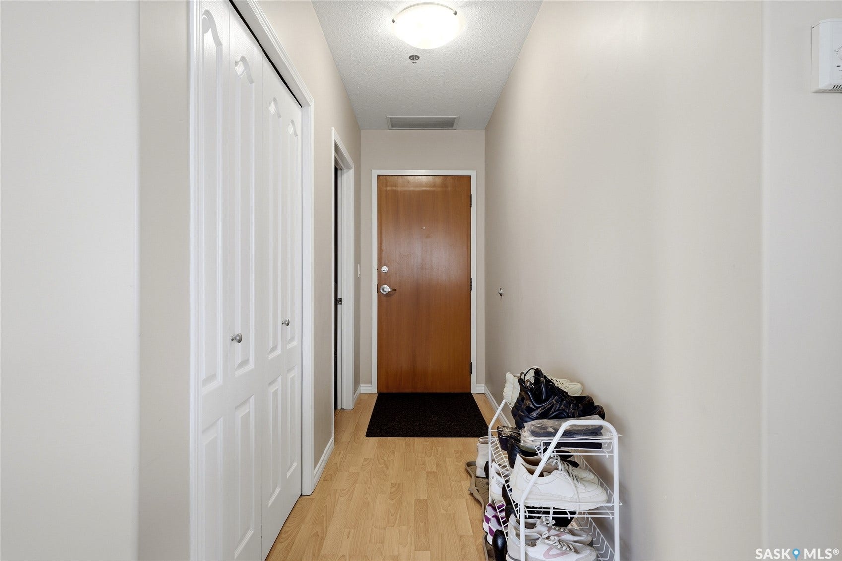 1914 Hamilton Street, #1007, Regina SK S4P 3N6 Entryway with wood-finish flooring, white bifold closet doors, and a flush-mount ceiling light fixture