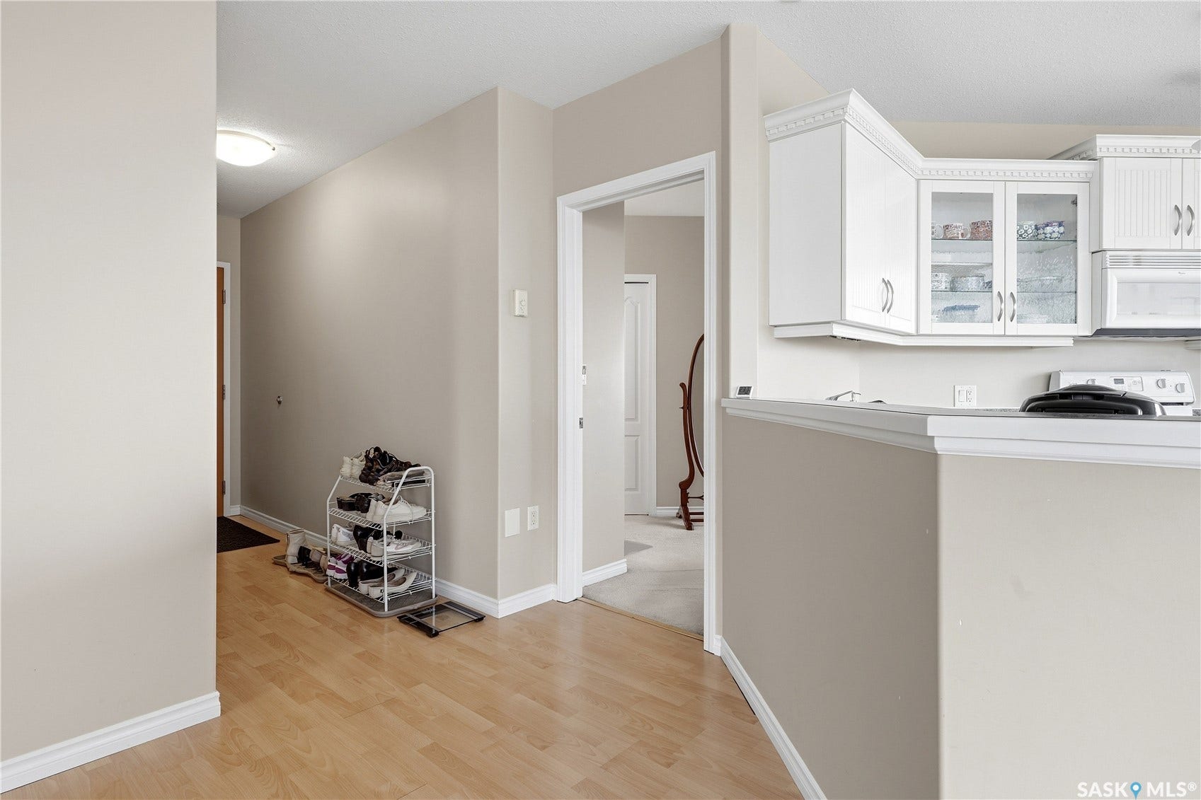 1914 Hamilton Street, #1007, Regina SK S4P 3N6 Wood-finish flooring, white cabinetry with glass inserts, recessed lighting, and a neutral wall color