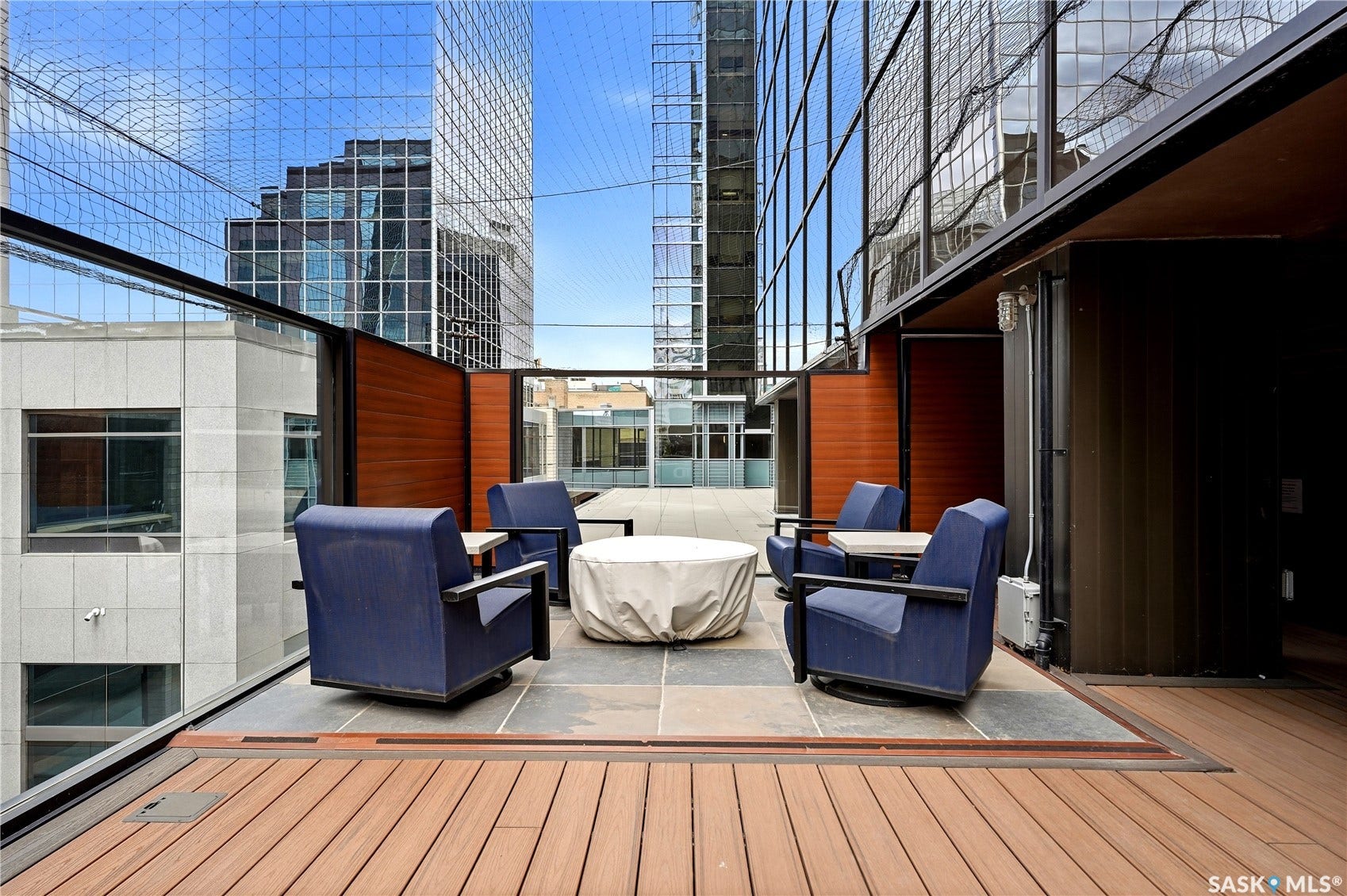 1914 Hamilton Street, #1007, Regina SK S4P 3N6 Expansive outdoor patio featuring wood-finish decking, stone-tiled seating area, and glass safety railing