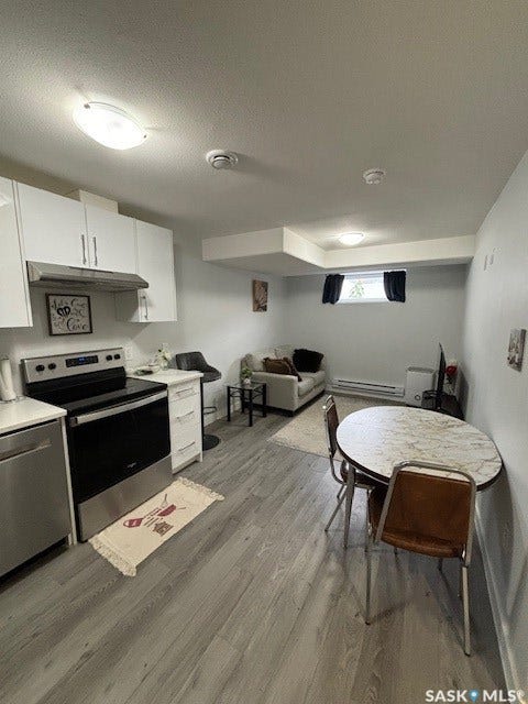 Kitchen featuring white upper and lower cabinetry, stainless steel appliances, and a range hood