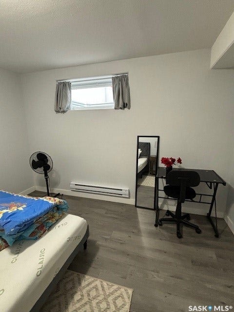 Light-toned wood-finish flooring, white walls, and a window with a curtain rod