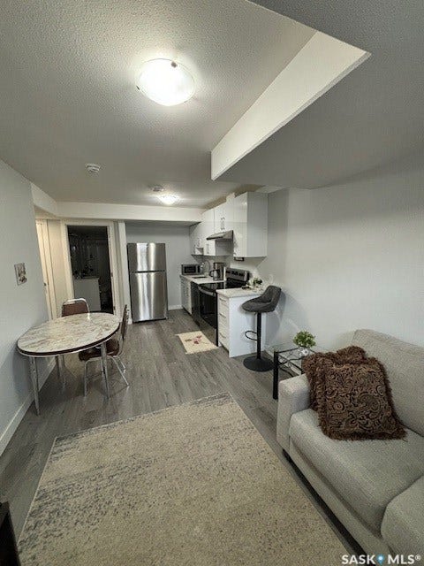 Open-concept living space with wood-finish flooring, white walls, and recessed lighting