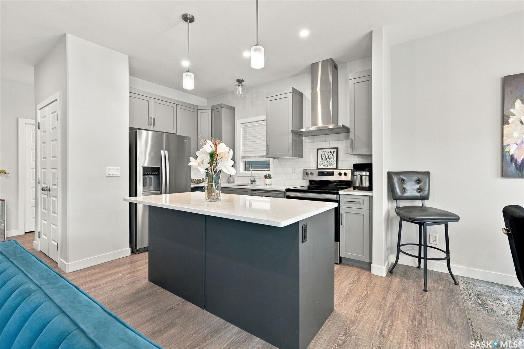 Kitchen featuring light gray cabinetry, stainless steel appliances, a white tile backsplash, and a central island with a white countertop