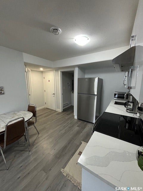 Kitchen featuring wood-finish flooring, stainless steel appliances, quartz countertops, and a ceiling-mounted light fixture