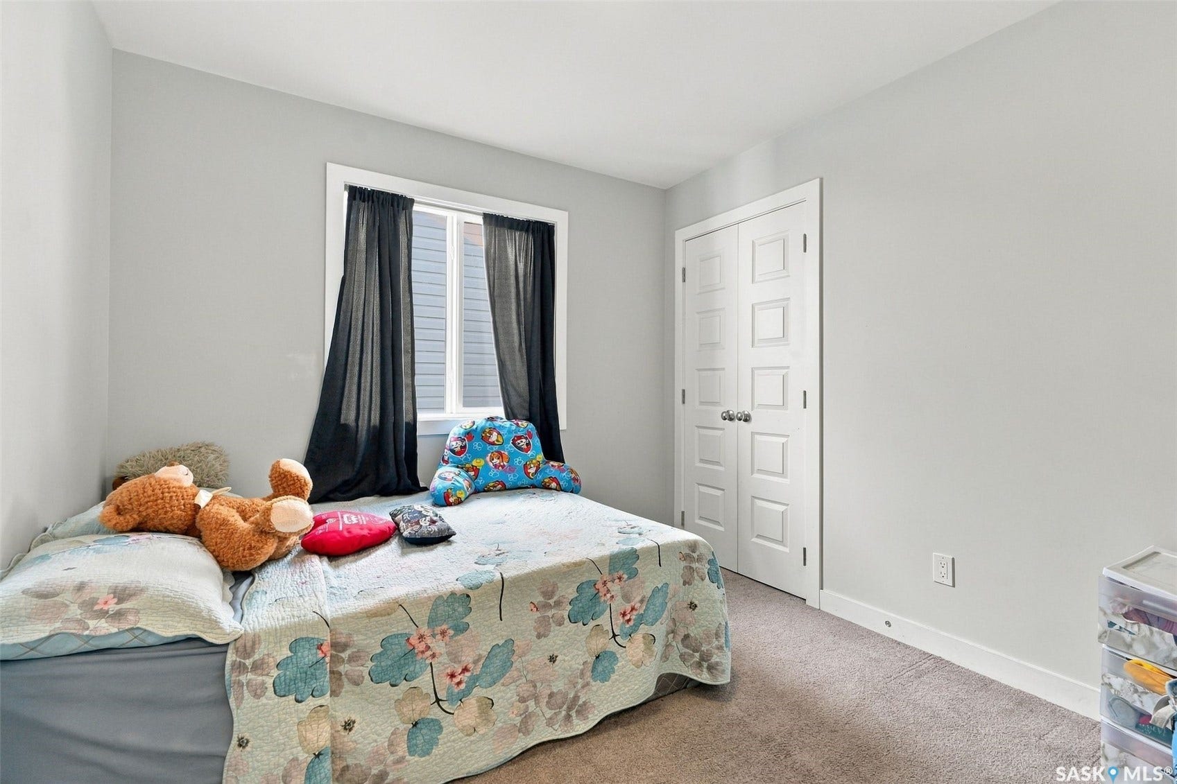 Neutral gray wall paint, white-framed window, textured carpet flooring, white paneled doors, and white trim