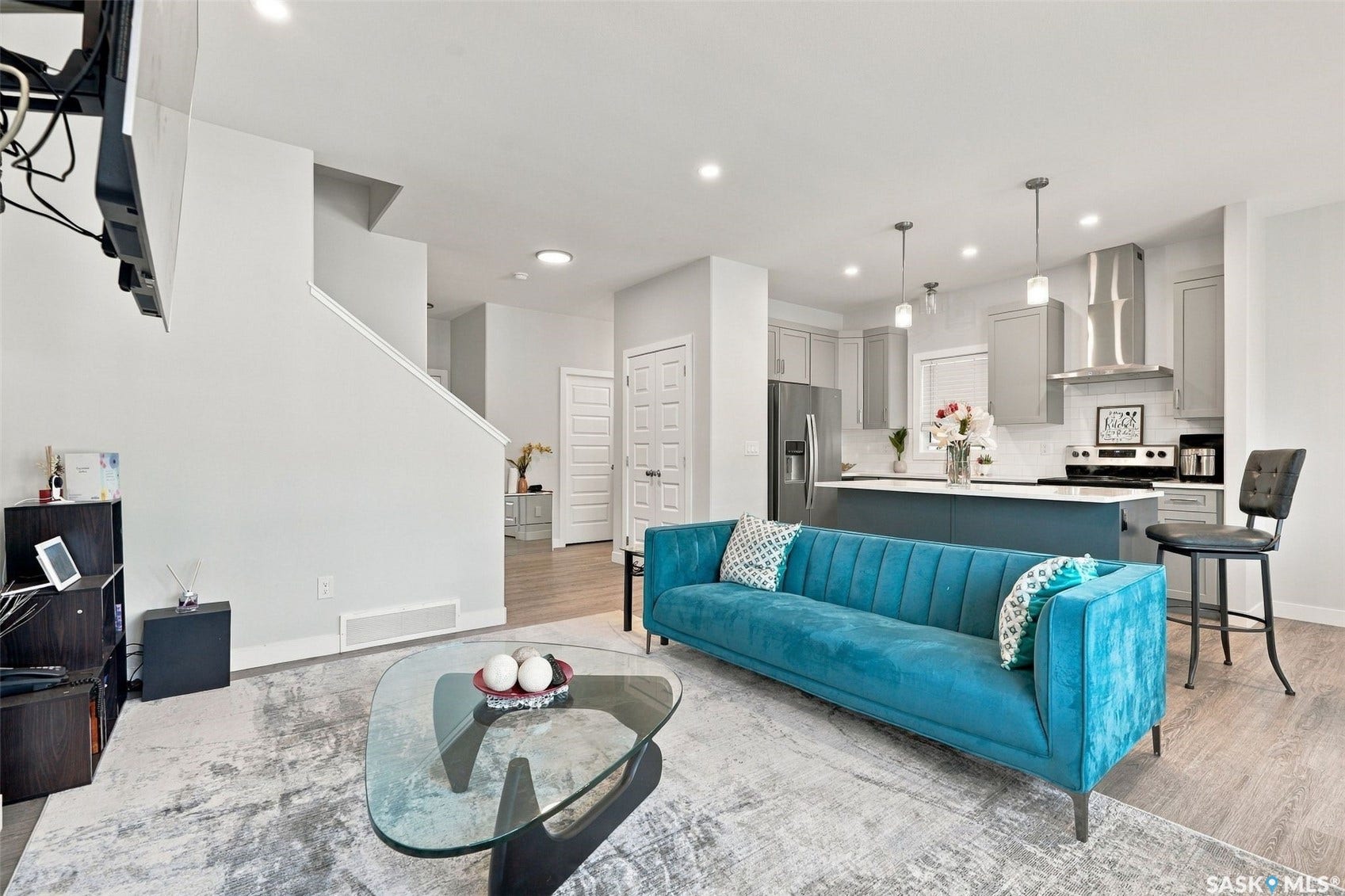 Open-concept living space featuring wood-finish flooring, recessed lighting, and a kitchen with an island, pendant lighting, and stainless steel appliances