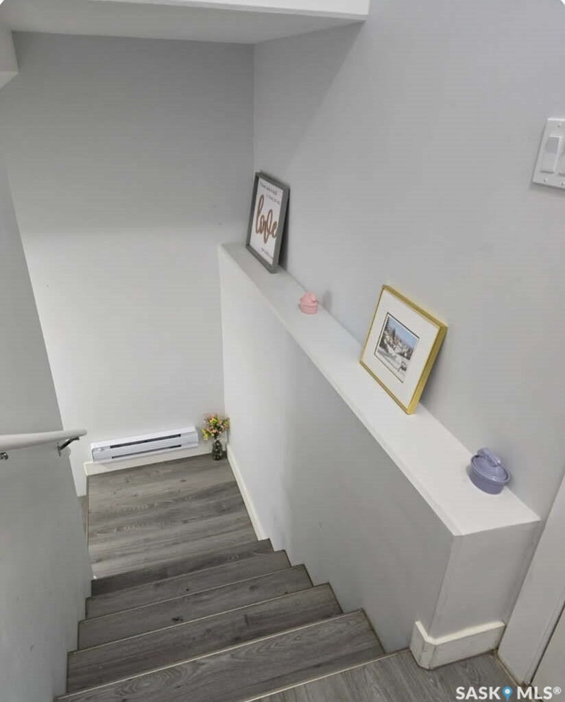 Staircase with wood-finish treads and risers, white walls, and a built-in wall shelf