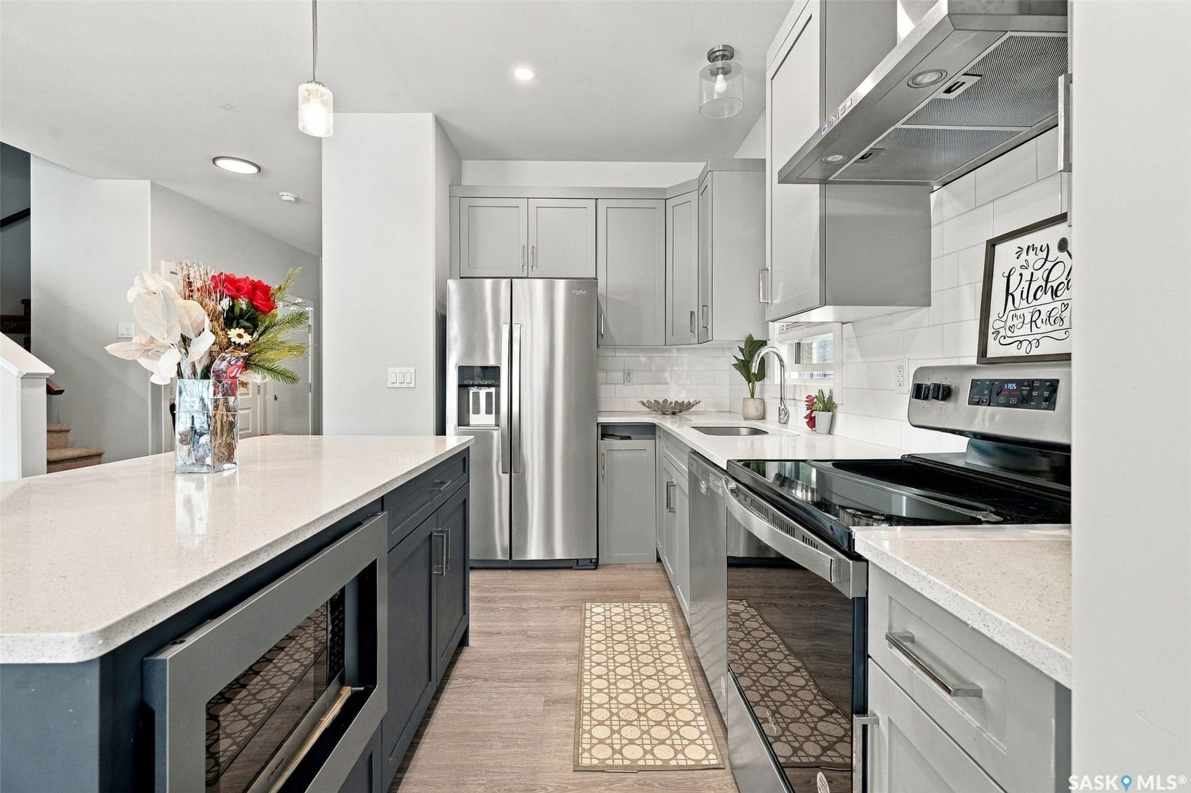 Kitchen featuring light-colored cabinetry, white subway tile backsplash, stainless steel appliances, and a central island with a built-in microwave
