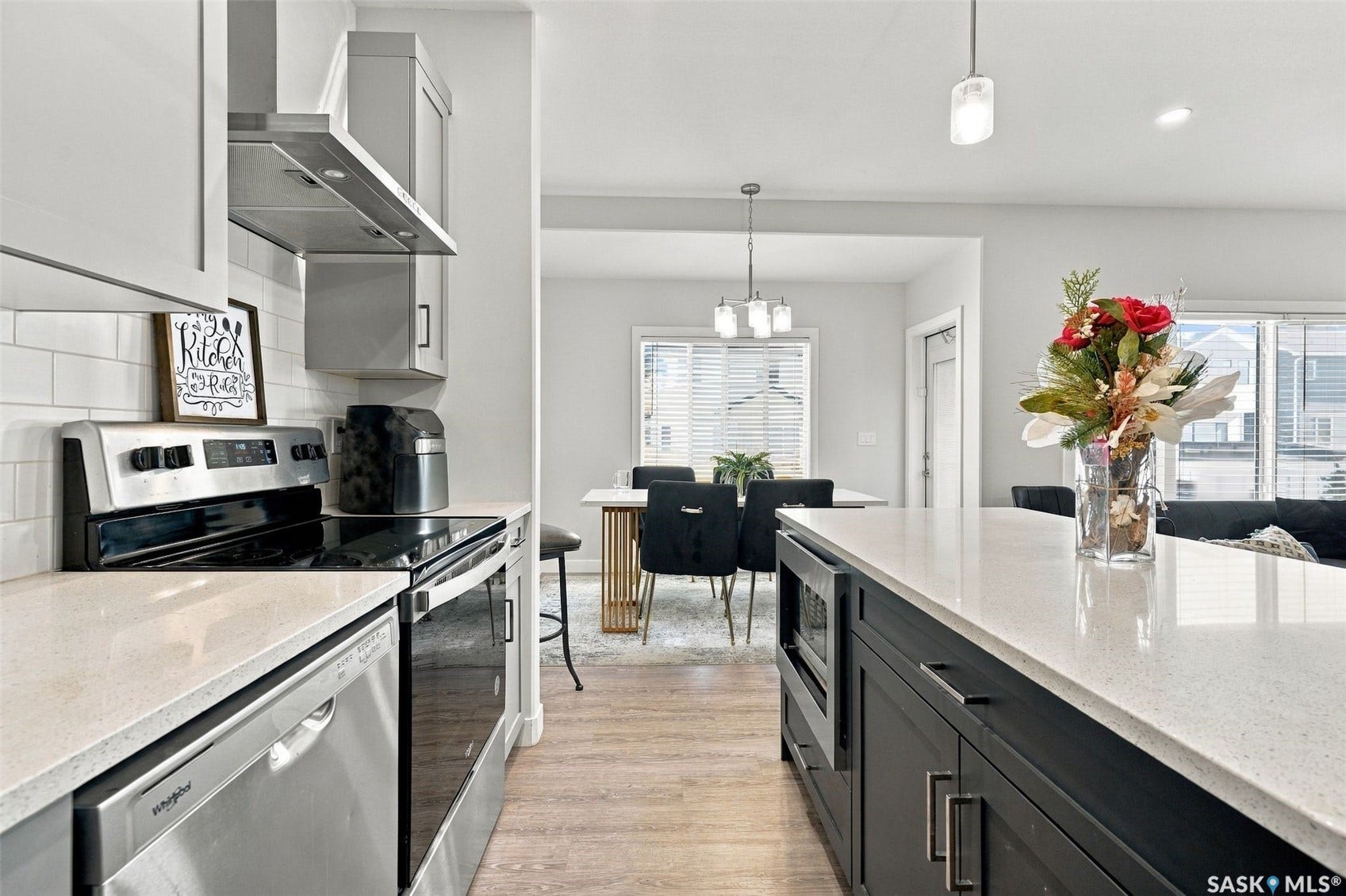 Kitchen featuring light wood-finish flooring, white subway tile backsplash, stainless steel appliances, a range hood, and an island with a built-in microwave