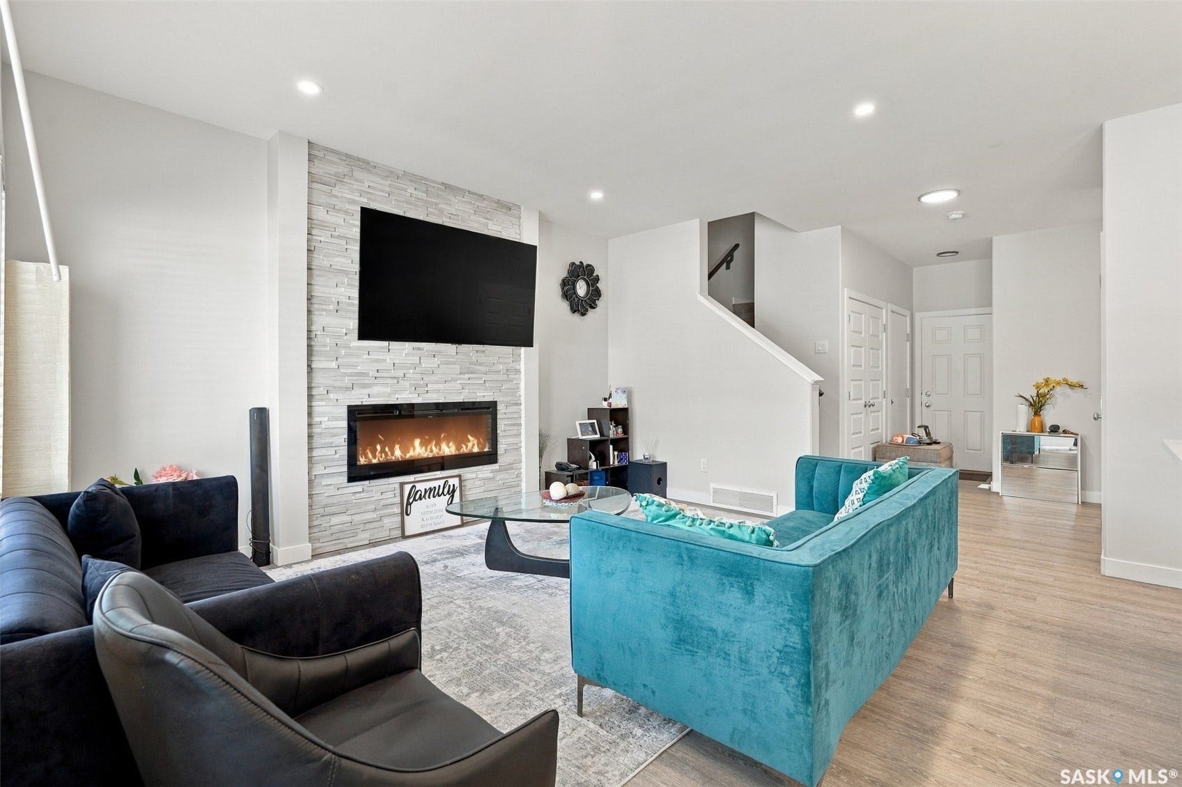 Living area featuring a floor-to-ceiling accent wall with a linear fireplace, recessed lighting, and wood-finish flooring