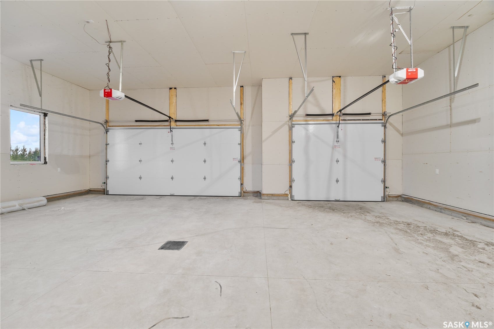 12 Elkwood Cove, Dundurn Rm No SK S7C 0C5 Two-bay garage with automatic door openers, a concrete floor, and a window for natural light