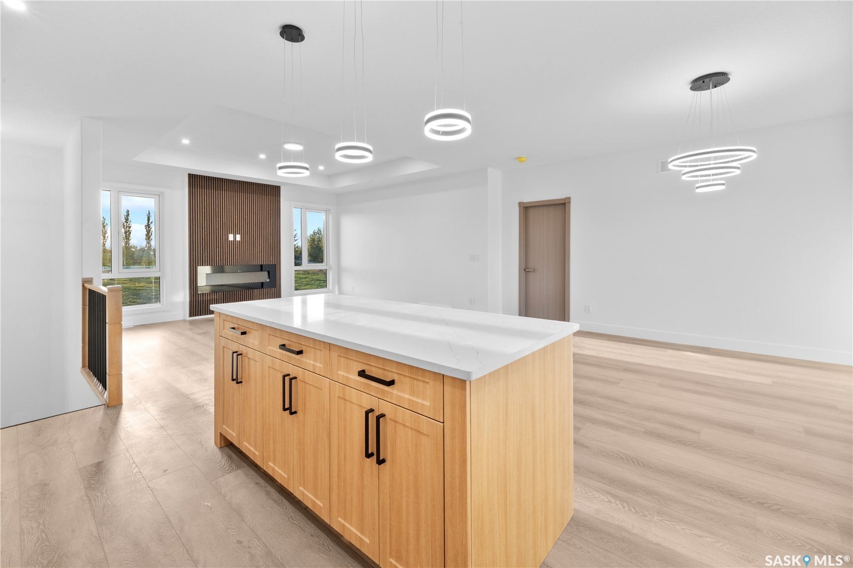 12 Elkwood Cove, Dundurn Rm No SK S7C 0C5 Open-concept living area featuring a kitchen island with stone countertop, light wood-finish cabinetry, and black hardware