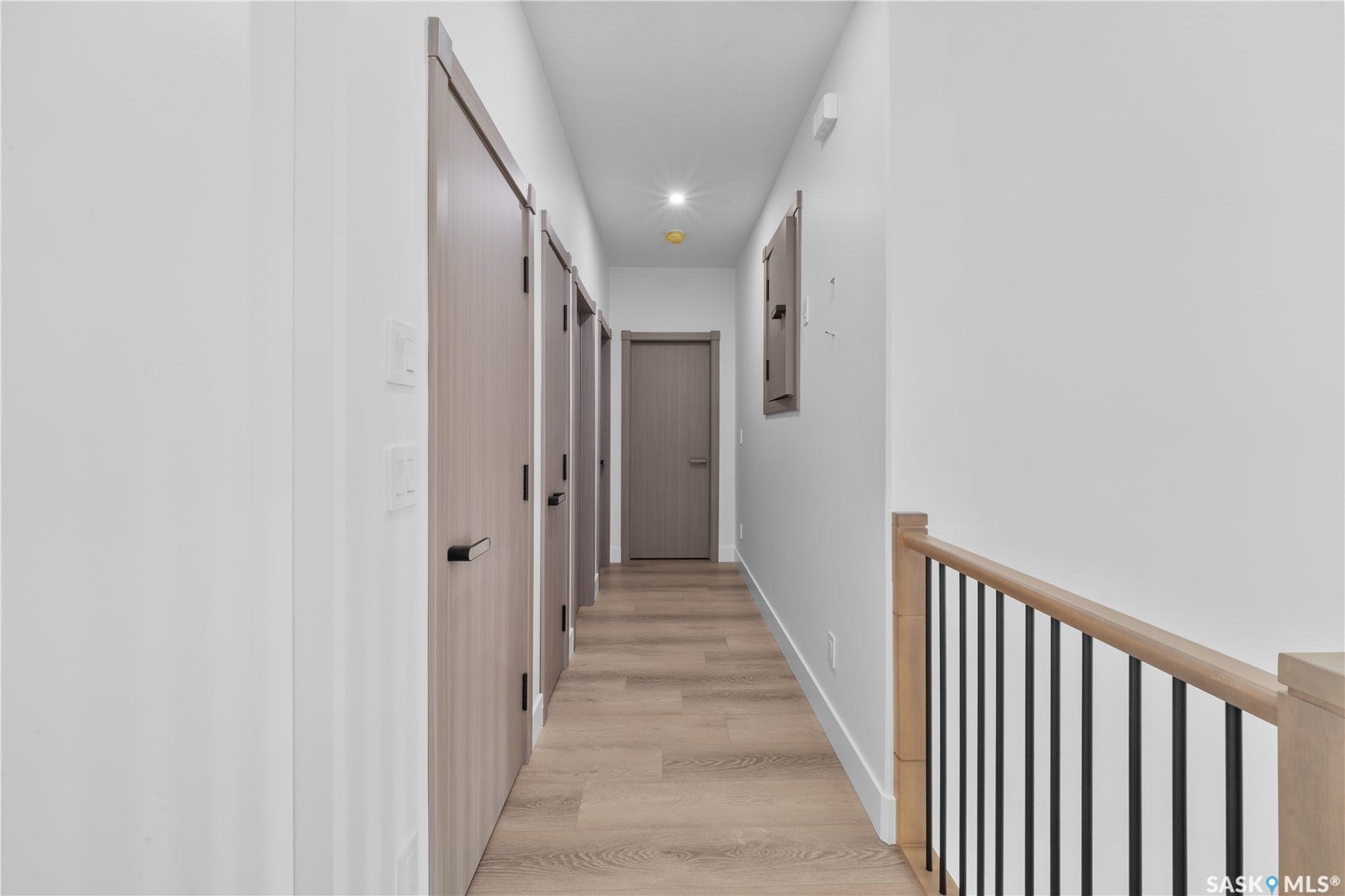 12 Elkwood Cove, Dundurn Rm No SK S7C 0C5 Wood-finish flooring, contemporary doors with matte black hardware, recessed ceiling lighting, and a wood handrail with black iron balusters