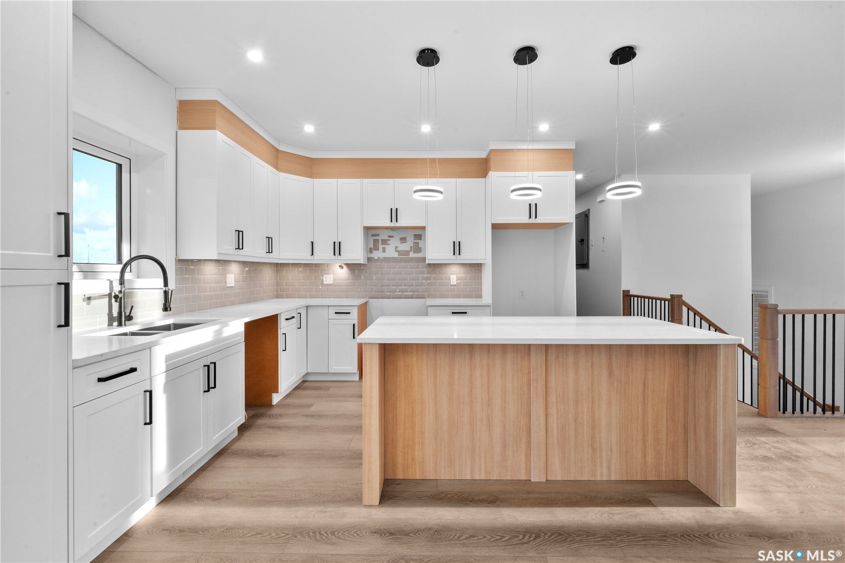 12 Elkwood Cove, Dundurn Rm No SK S7C 0C5 Kitchen featuring white cabinetry, light wood-finish accents, and a large center island with a white countertop