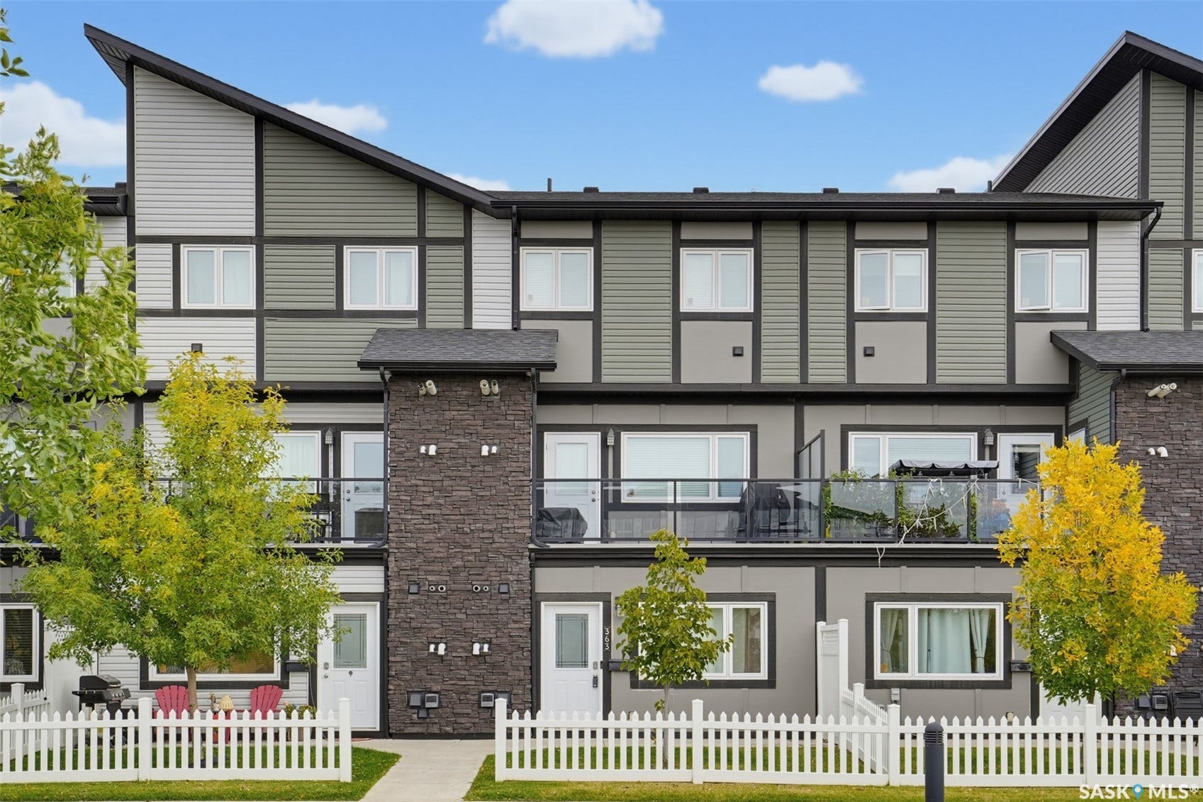 Multi-level exterior featuring contemporary siding, stone accent columns, multiple windows, and private balconies with glass railings