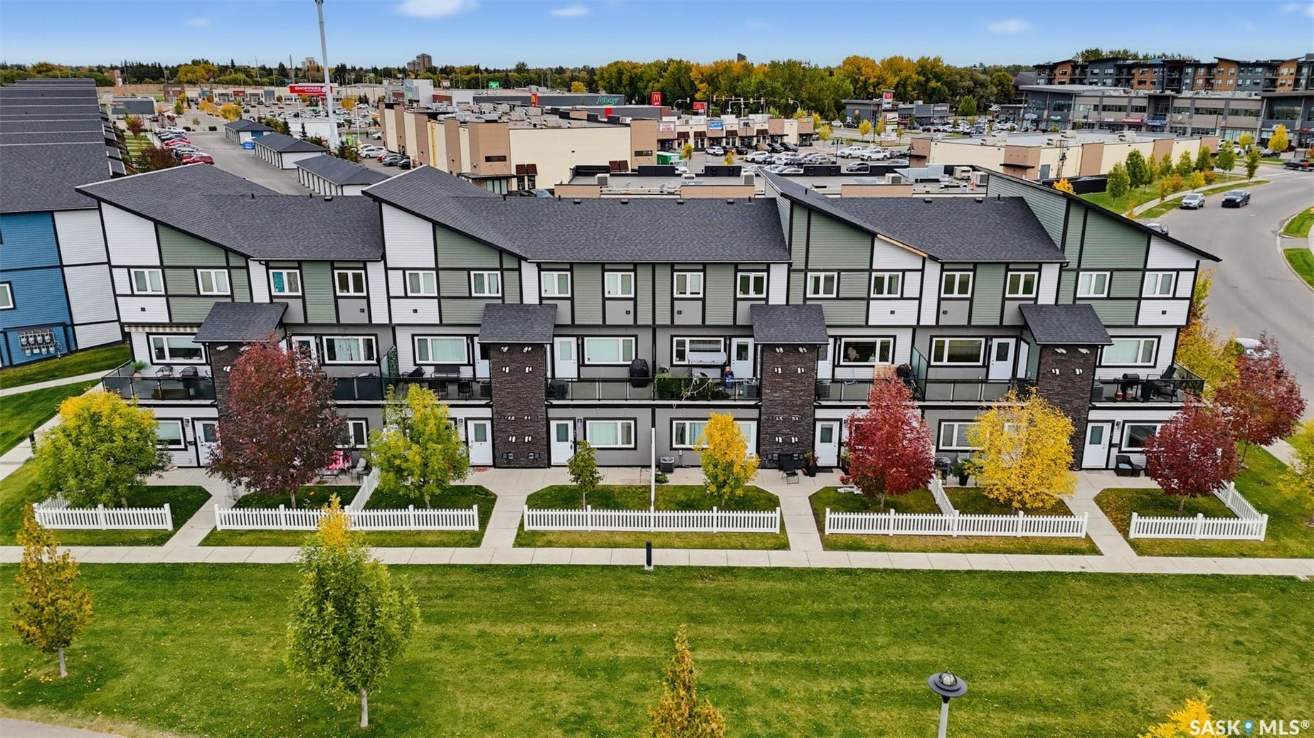 Modern multi-level townhome featuring a dark shingled roof and light-colored siding