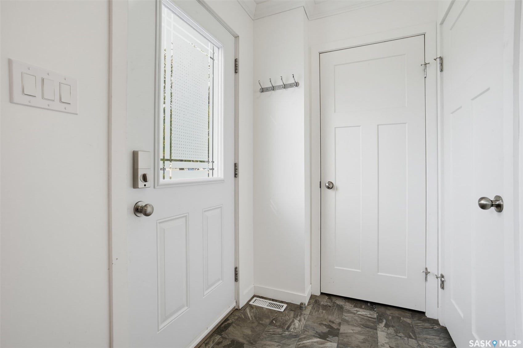 Entryway featuring a paneled door with decorative glass, a smart lock, and dark-toned flooring