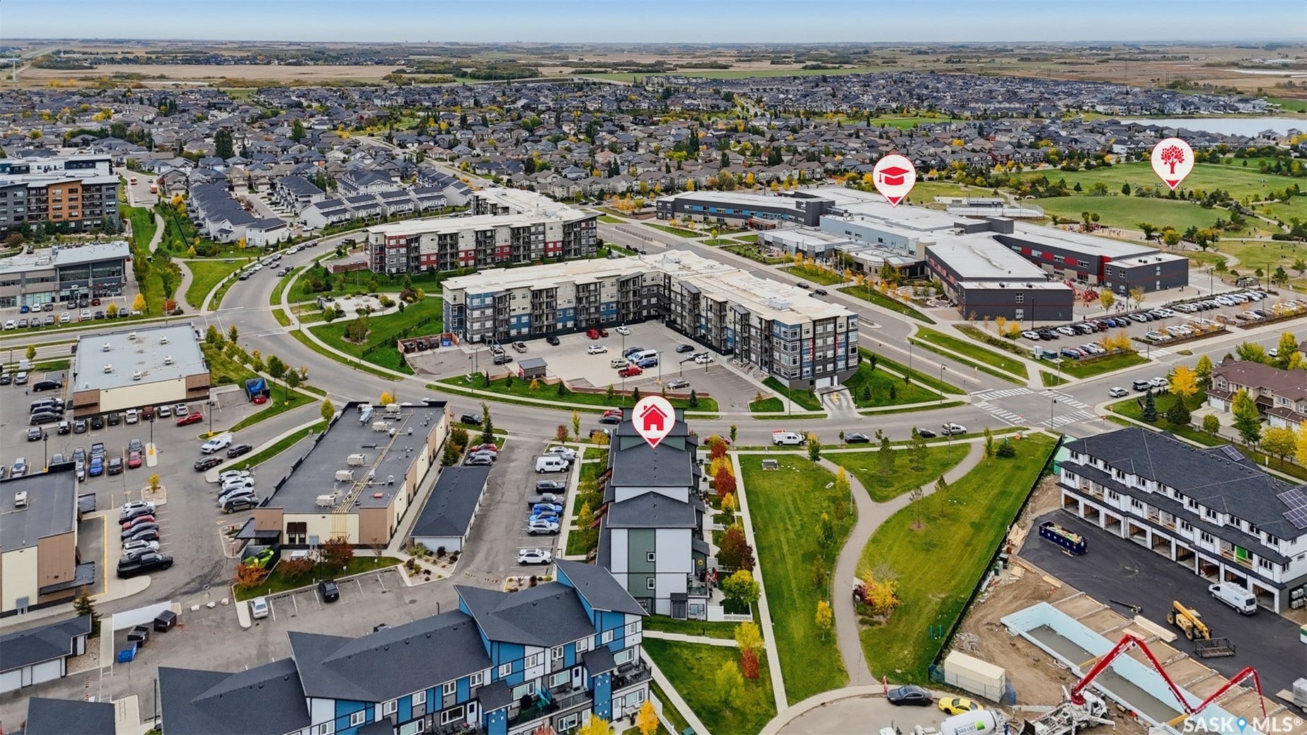 Aerial perspective of a developed community featuring multi-story residential buildings, commercial structures, and paved roadways