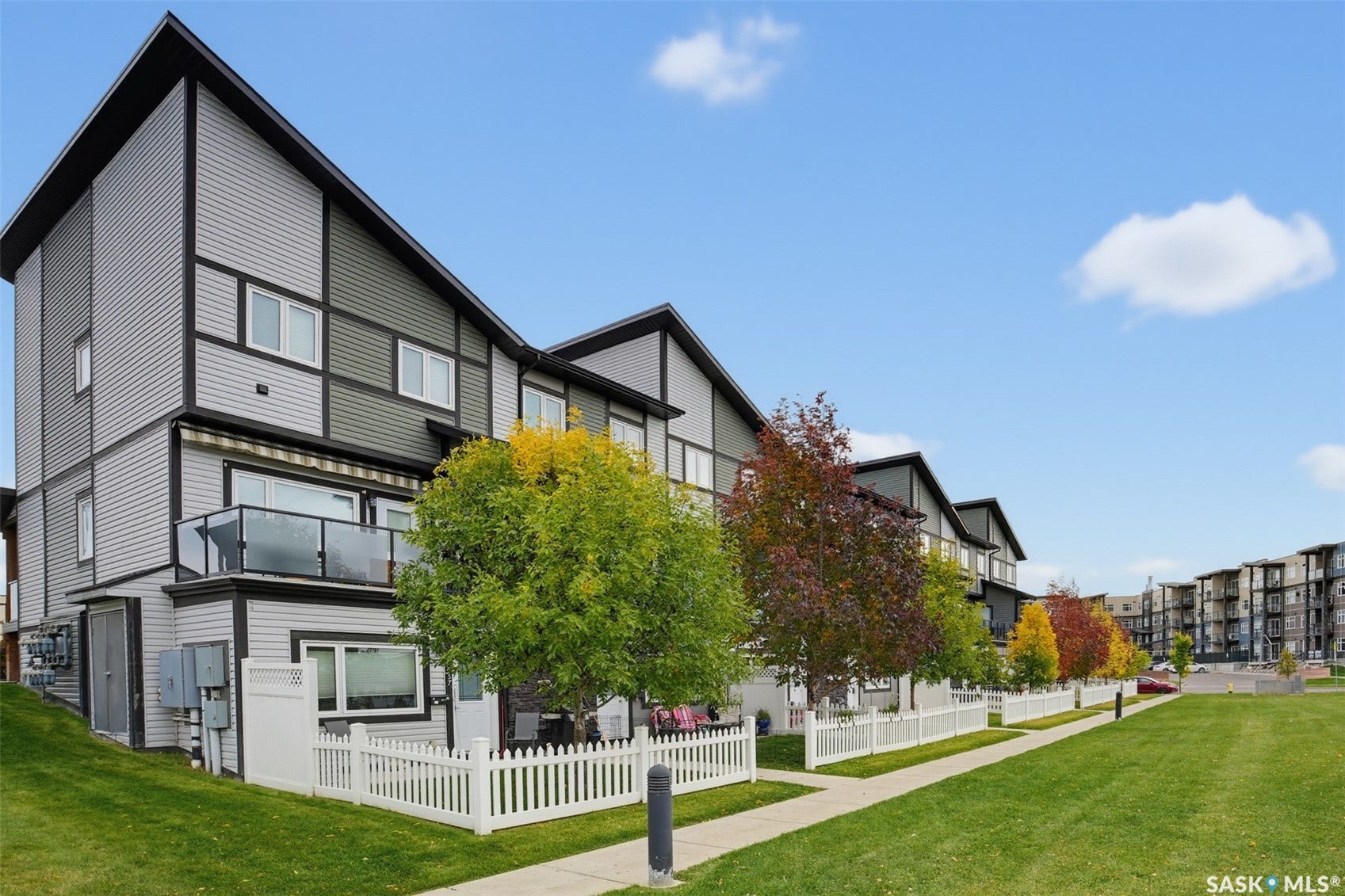 Modern townhome exterior with mixed siding, multiple windows, and an upper-level balcony with glass railings
