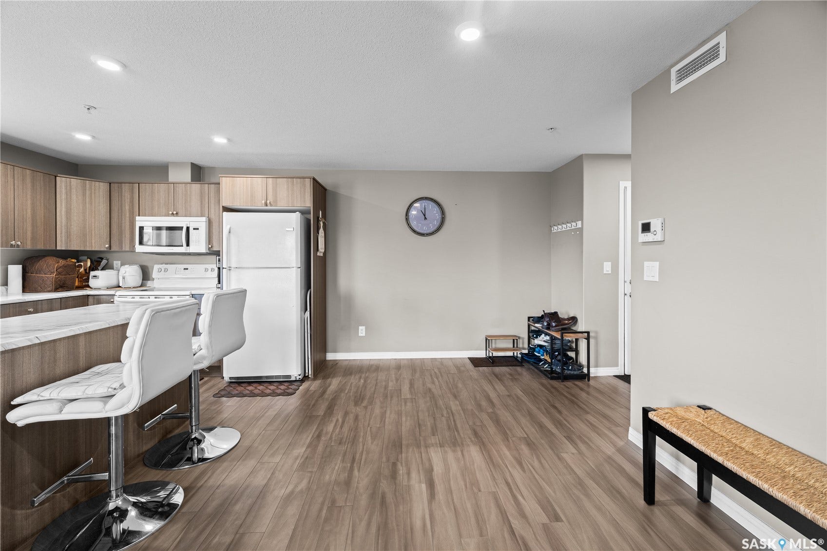 Kitchen featuring wood-finish cabinetry, white appliances, and a marble-look countertop with a breakfast bar