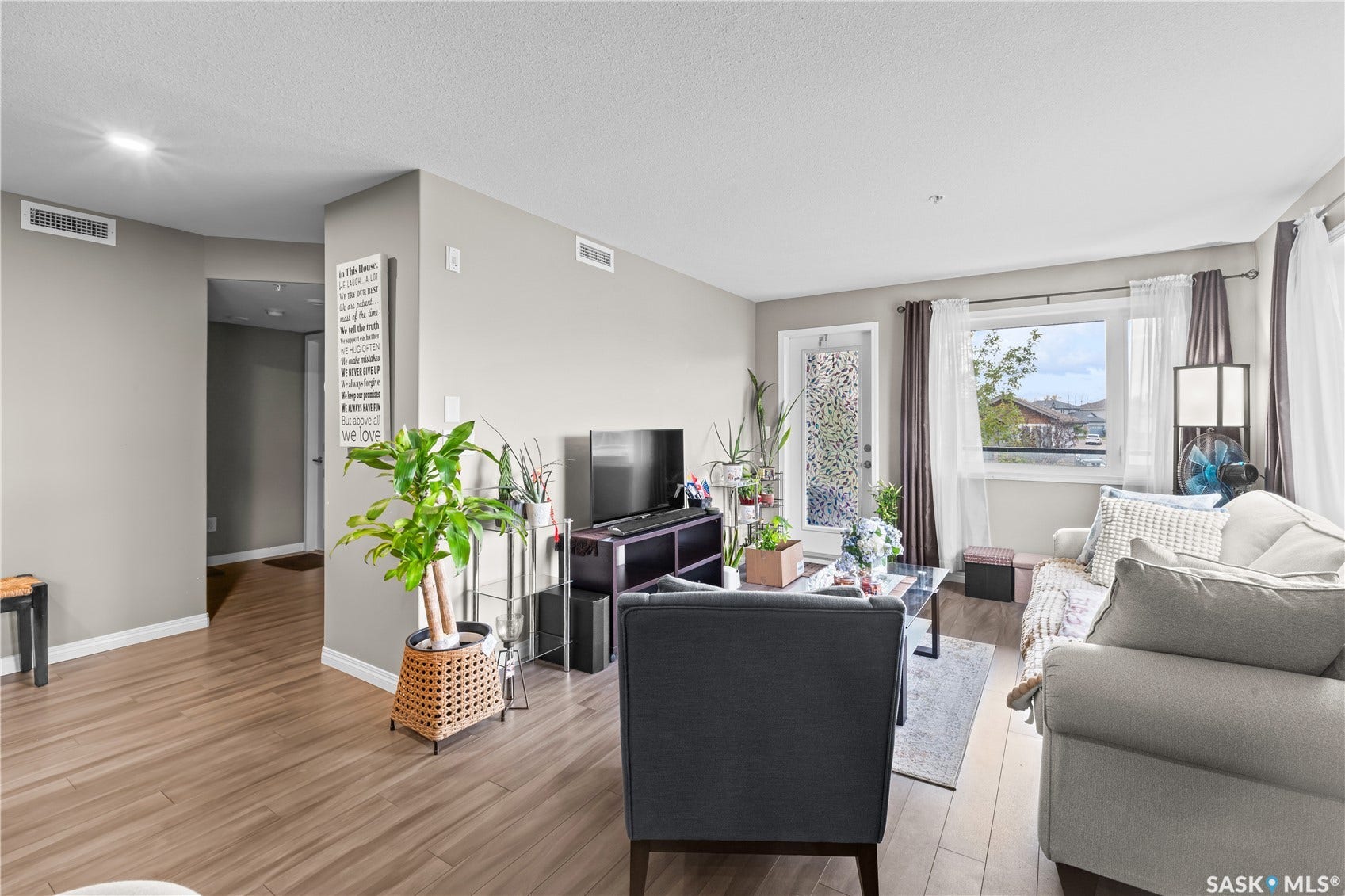 Living area featuring wood-finish flooring, light-toned wall paint, a window with exterior scenery, and a glass-paneled door