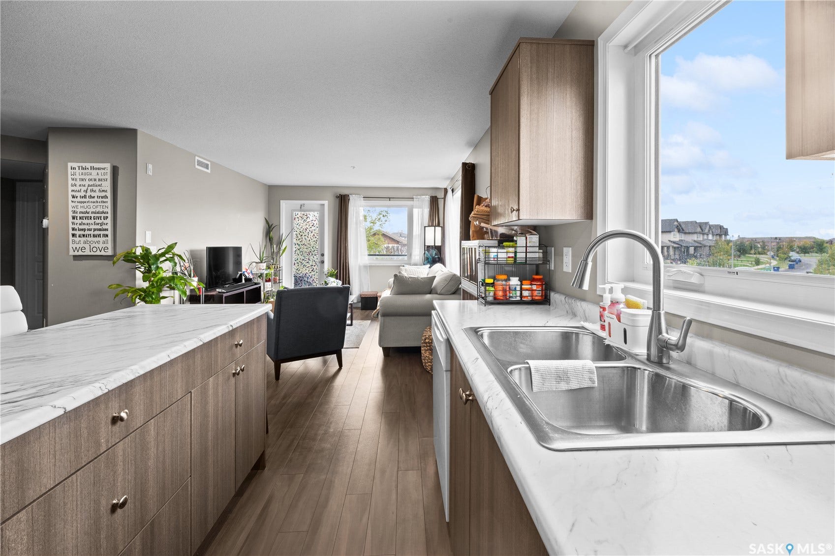 Kitchen with wood-finish cabinetry, stainless steel double basin sink, and ample countertop space