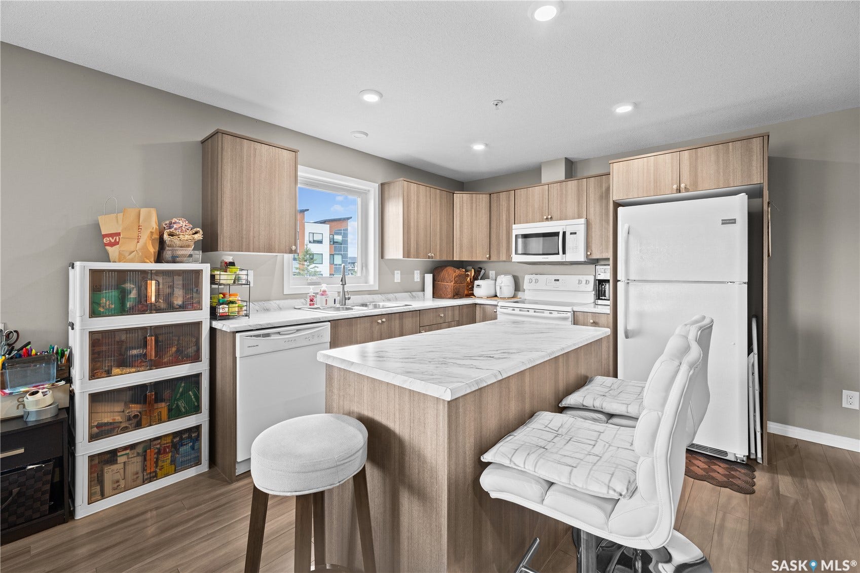 Kitchen featuring wood-finish cabinetry, white appliances, recessed lighting, and a kitchen island with a stone countertop