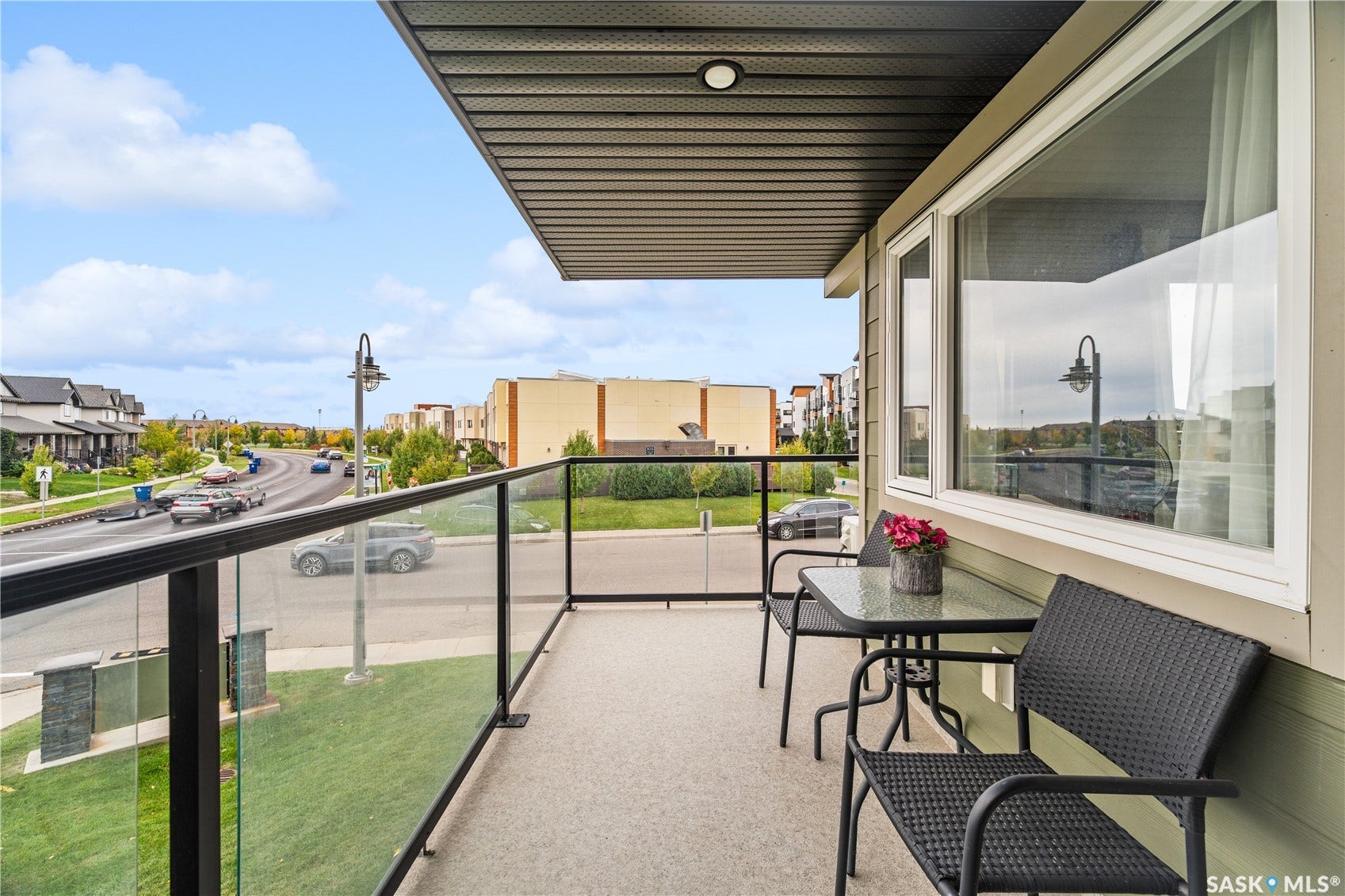 Private balcony featuring glass panel railings, textured flooring, and a soffited ceiling with an integrated light fixture