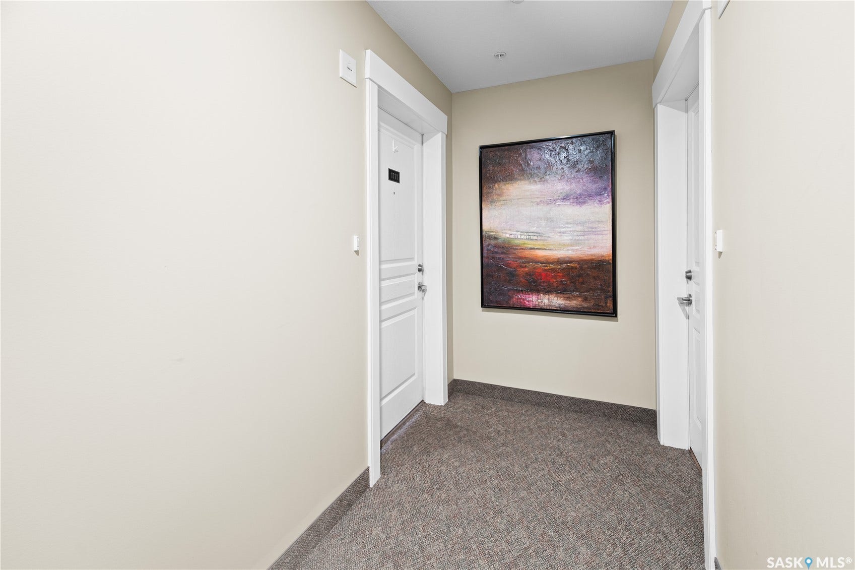Hallway with neutral wall paint, carpet flooring, and white trim