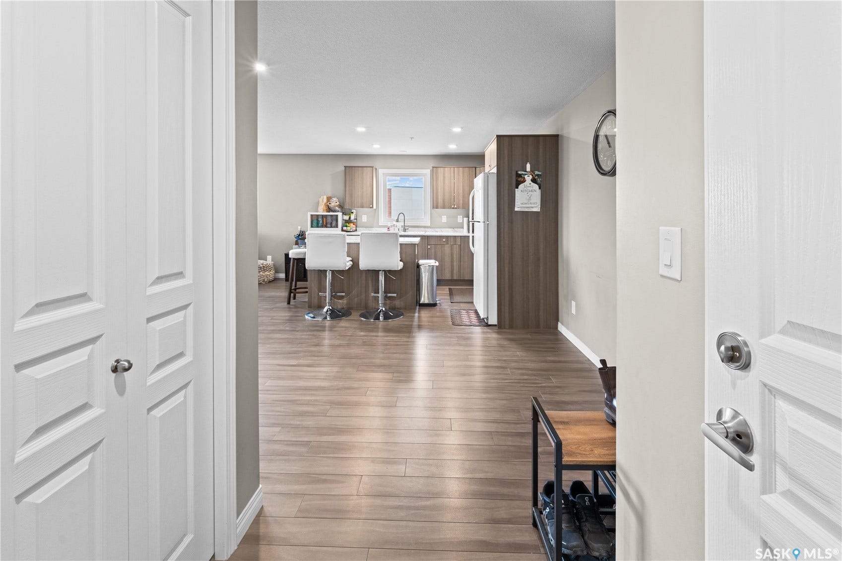 Wood-finish flooring throughout, recessed lighting, and a kitchen featuring a peninsula with seating, stainless steel appliances, and wood-finish cabinetry