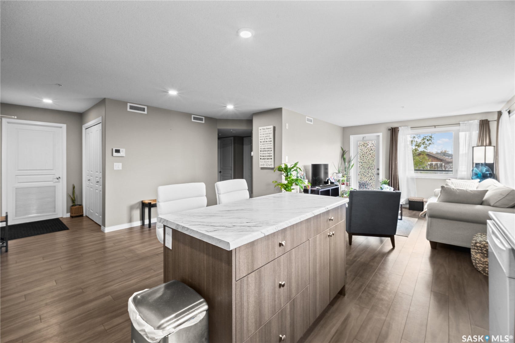 Open concept living area featuring wood-finish flooring, recessed lighting, and a kitchen island with a stone-finish countertop