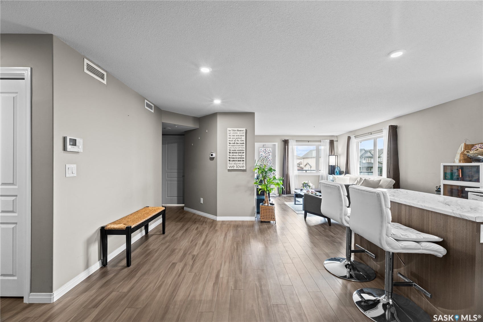 Open-concept living space featuring wood-finish flooring, recessed lighting, and a kitchen island with a light-toned countertop