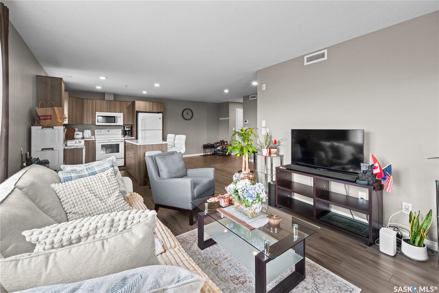 Open-concept living area with wood-finish flooring, recessed lighting, and a kitchen featuring wood-finish cabinetry and white appliances