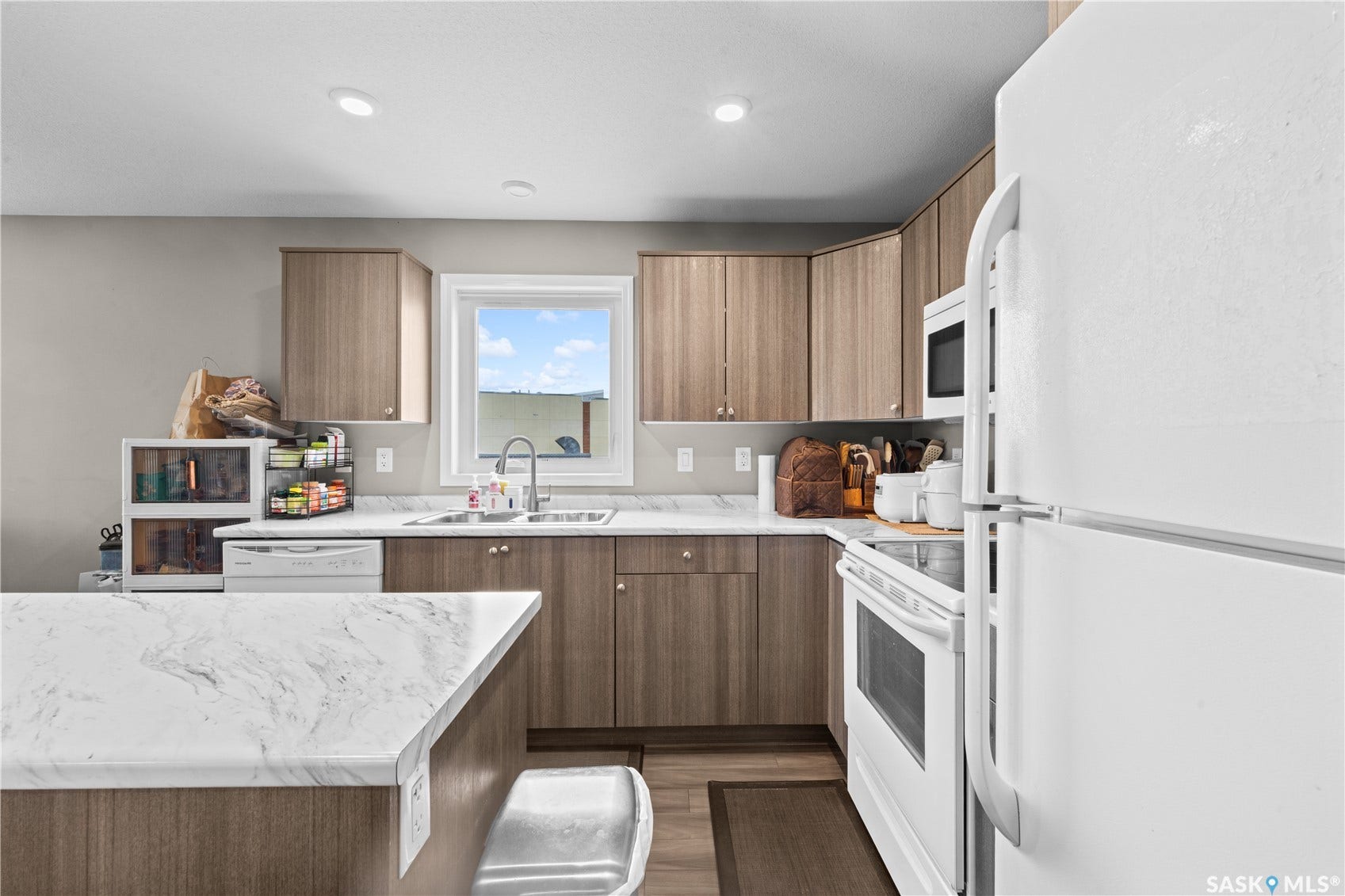 Kitchen featuring wood-finish cabinetry, white appliances, and light-toned countertops
