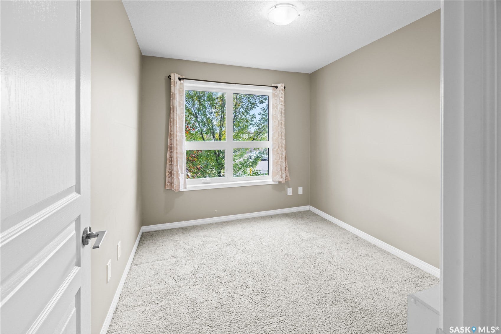 Neutral paint tones, light-colored carpeting, white trim, and a window with natural light