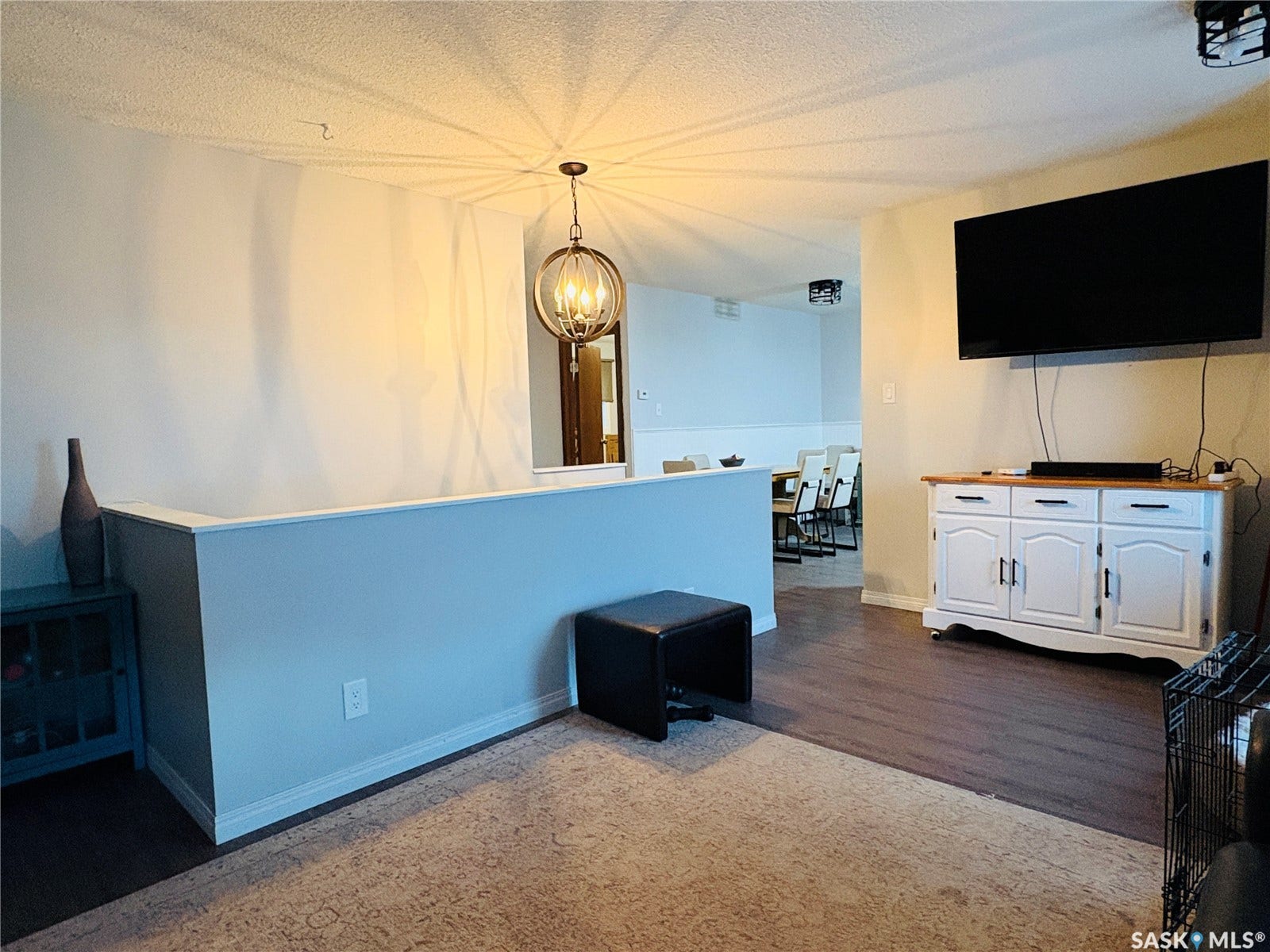 Open floor plan featuring wood-finish flooring, a contemporary chandelier, and a built-in half-wall