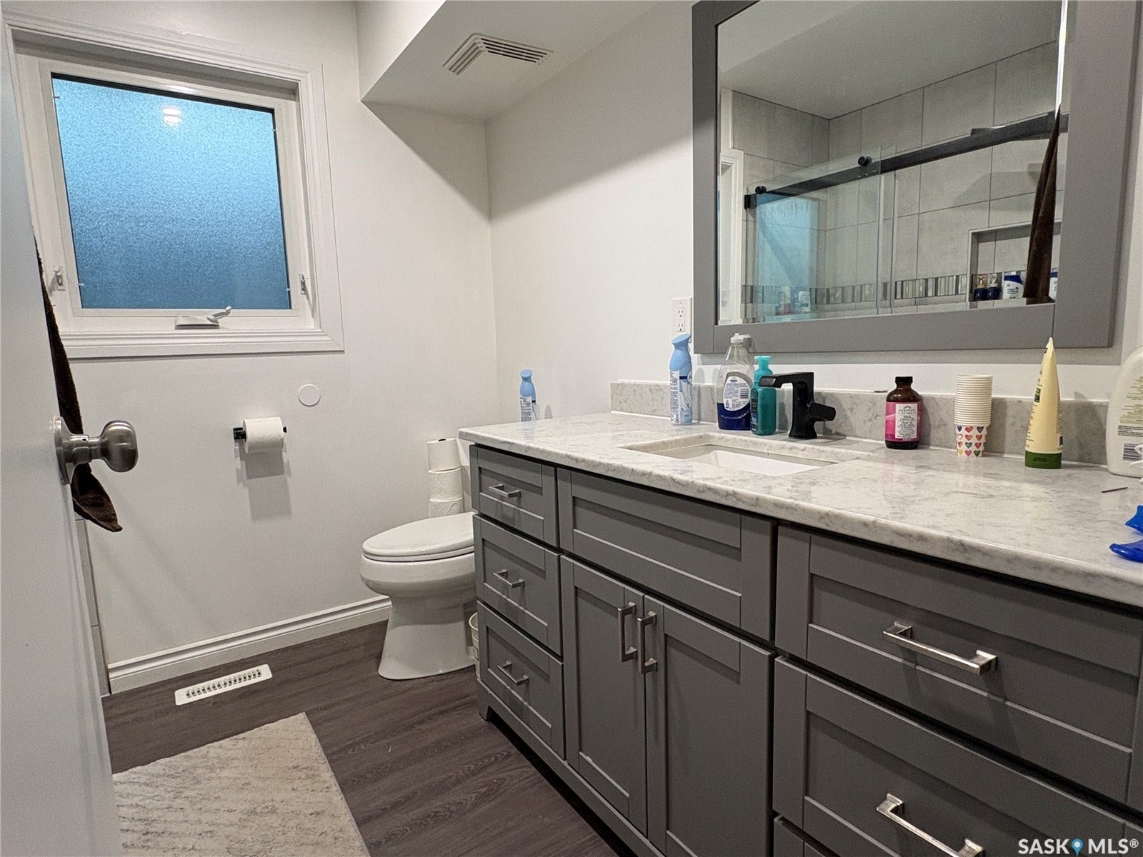 Contemporary bathroom featuring a grey vanity with a light-colored countertop, integrated sink, and black faucet