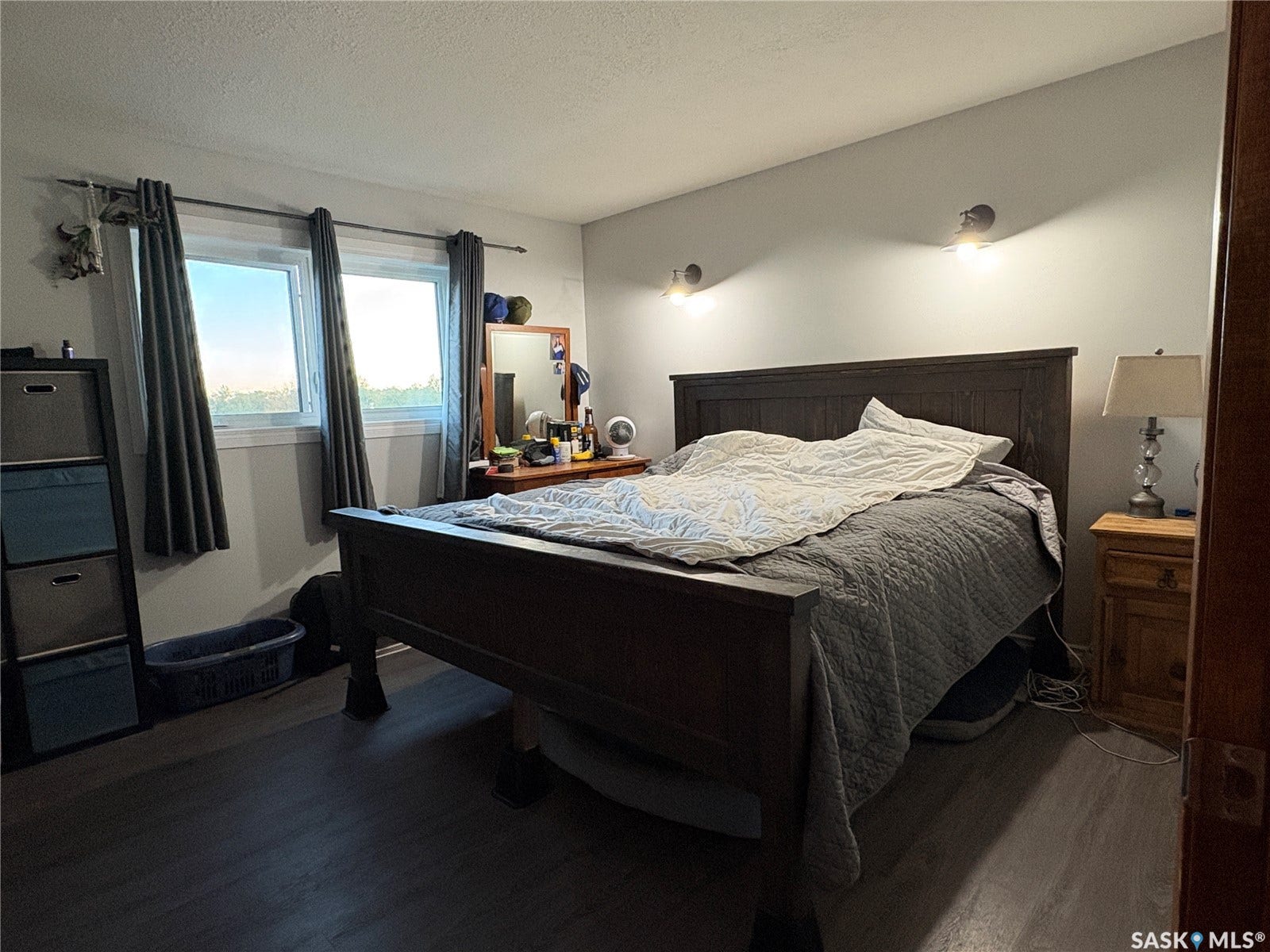 Dual windows providing natural illumination, wood-finish flooring, and wall-mounted sconce lighting